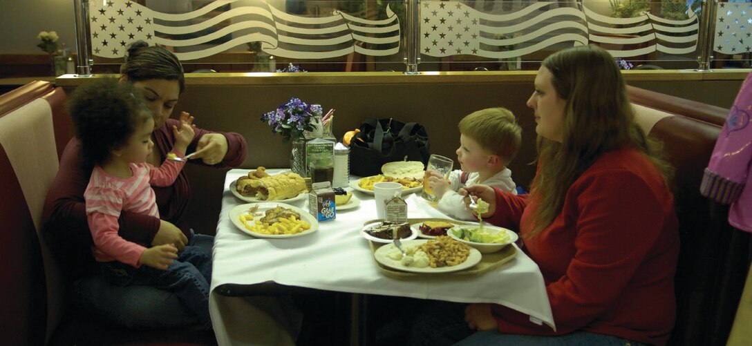 Maureen Elias and her daughter Agmaris, left, enjoy dinner at the dining facility with Michelle Hatch and her son Jonathan, right, as part of the deployed spouses dinner March 27. Their husbands are deployed together in Kuwait for eight months from the 316th Logistics Readiness Squadron. The DFAC and Airman Family Readiness Center provided a themed dinner for deployed spouses that included crafts, gifts, face painting, free toys for the kids and a cake. (U.S. Air Force photo/ Senior Airman Renae Kleckner)