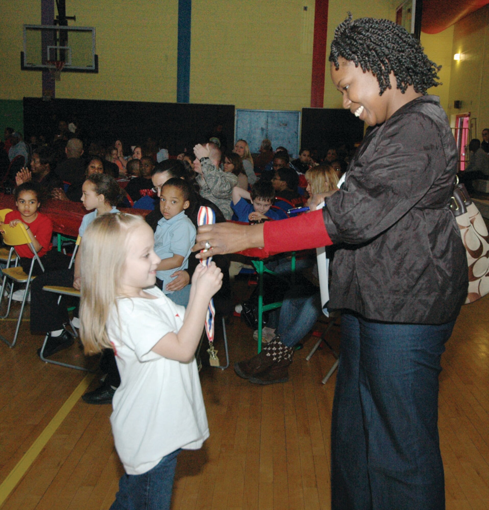 Serenity Miller, 7, receives a medal for cheerleading from Aujua Woods, 316th Logistics Readiness Squadron order clerk and Youth Center cheerleading coach, during the awards portion of the Sports Banquet held at Andrews Youth Center March 27. Serenity is the daughter of Staff Sgt. Christopher Miller, an air transportation craftsman assigned to the  89th Aerial Port Squadron Special Air Mission Passenger terminal. (U.S. Air Force photo/ Bobby Jones)