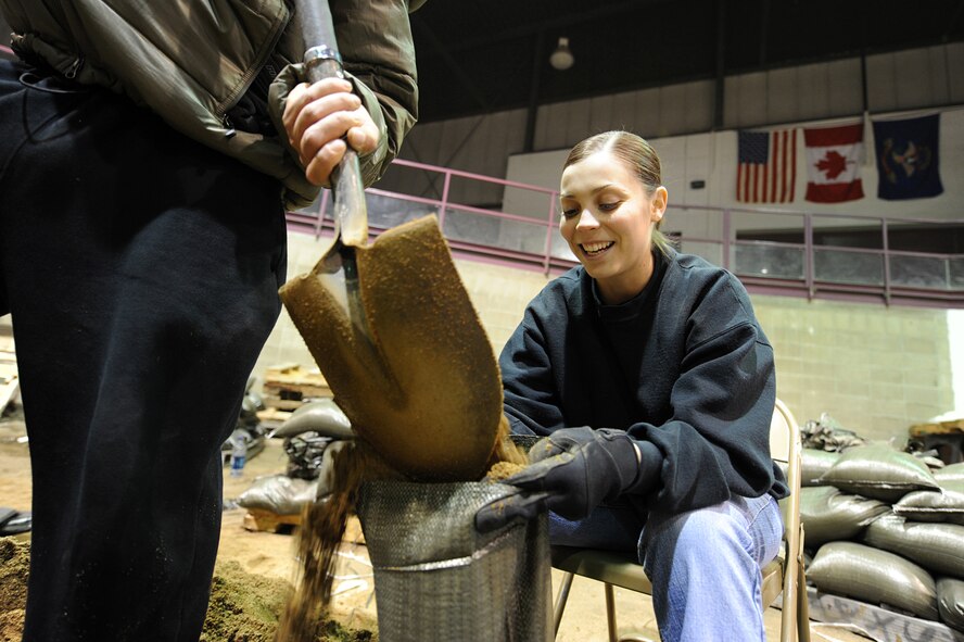 MINOT, N.D. – Senior Airman Ashley Woods, 91st Security Forces Group resource advisor, volunteers after work to build sand bags in the All Season’s Arena here April 1. Volunteers from the Minot area community and Minot Air Force Base reached the goal of filling 25,000 sandbags in the first two days alone. They will continue to help in this flood relief effort until 6 p.m. April 4. (U.S. Air Force photo by Senior Airman Kelly Timney)