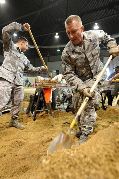 MINOT, N.D. – Senior Master Sgt. Ken York, chief of heavy repair attached to the 5th Civil Engineer Squadron, builds sand bags alongside fellow Airmen in the All Season’s Arena here April 1. Sergeant York is TDY here until June to aid with the snow removal process.  Volunteers from the Minot area community and Minot Air Force Base reached the goal of filling 25,000 sandbags in the first two days alone. They will continue to help in this flood relief effort until 6 p.m. April 4. (U.S. Air Force photo by Senior Airman Kelly Timney)