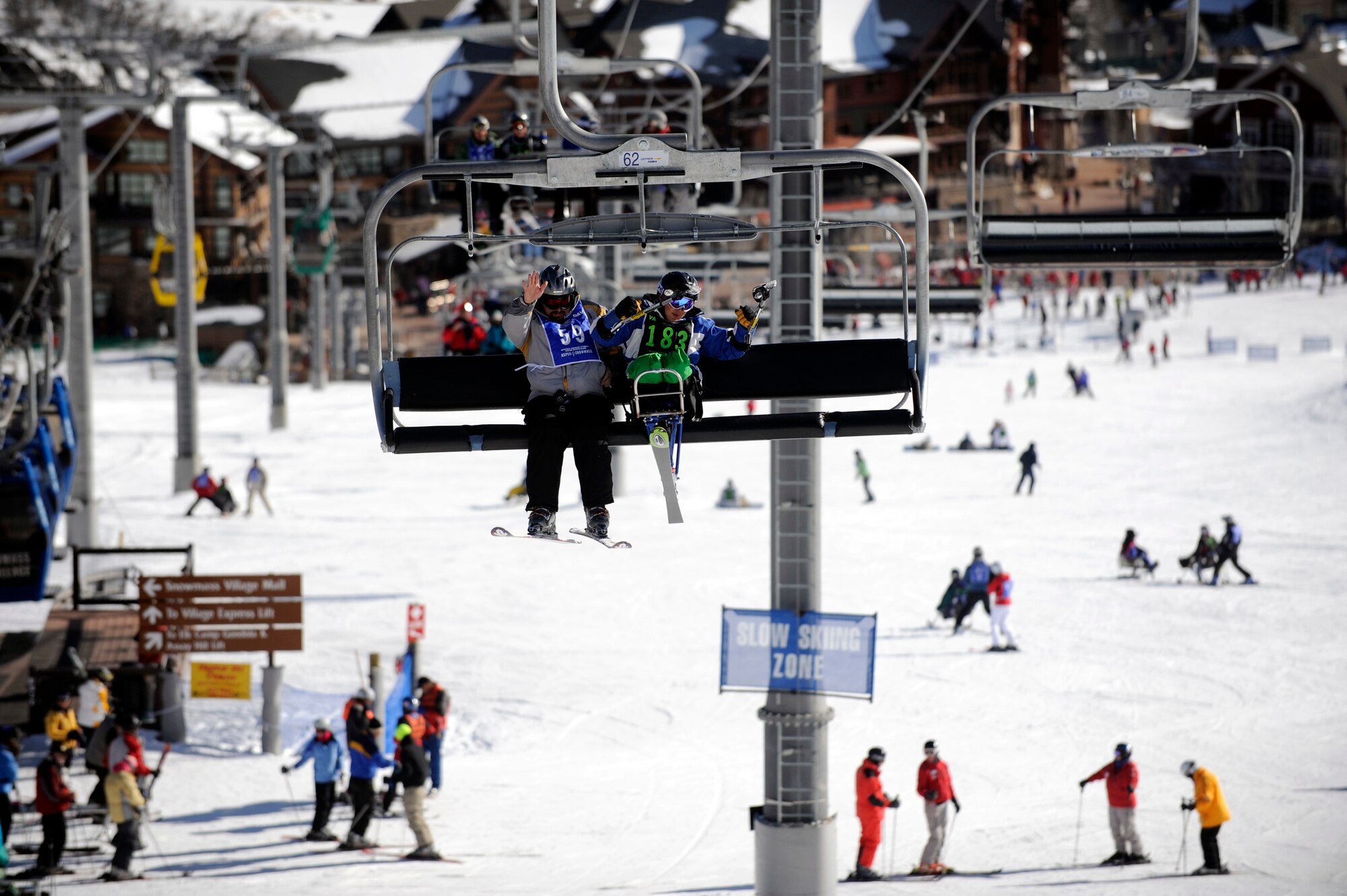 Mark Finken and Senior Airman Kevin Krogh wave at people below them as they ride the ski lift to the top of Snowmass Village Apr. 2 during the 23rd National Disabled American Veterans Winter Sports Clinic in Snowmass Village, Colo. Airman Krogh lost both legs in a major car accident in 2007 and this is his first year attending the sports clinic. Airman Krogh is assigned to Fort Sam Houston in San Antonio. Finken is a ski instructor for the sports clinic. (U.S. Air Force photo/Staff Sgt. Desiree N. Palacios)