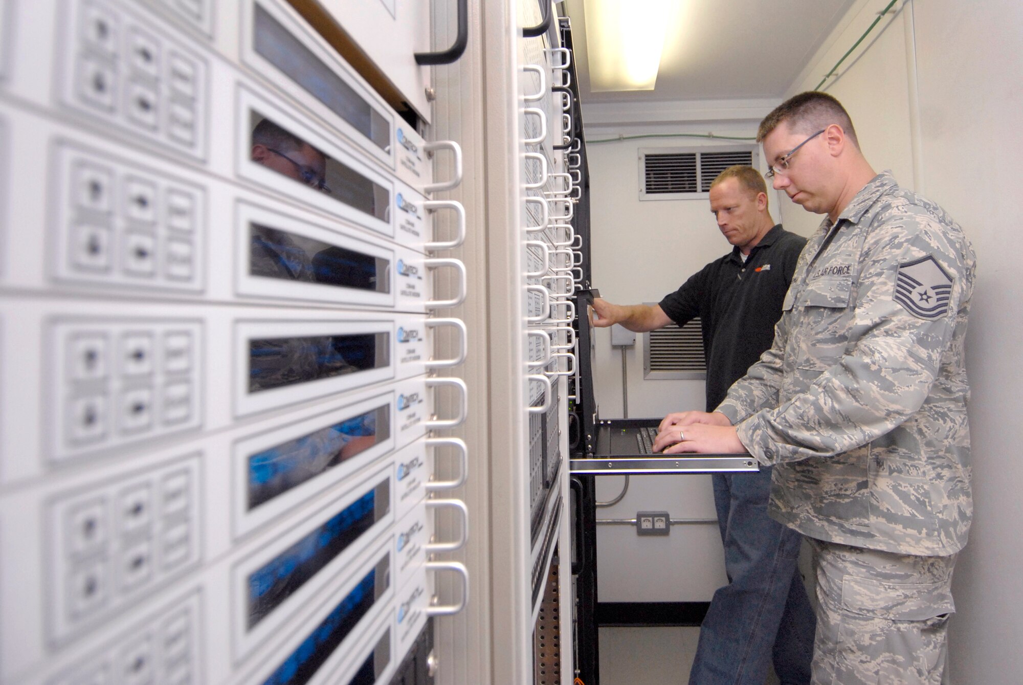 Mike Kaupp, DRS Technologies Site Manager, and Master Sgt. Christopher Hedman, NCO in charge of Technical Control, perform routine maintenance checks in the Deployable KU Band Earth Terminal (DKET), Mar. 30, 2009, at an undisclosed location in Southwest Asia.  Members from Tech Control help maintain communication for 75% of the Air Force units throughout the U.S. Central Command's Area of Responsibility.  Mike Kaup hails from San Clemente, Calif. and Master Sgt. Hedman hails from Goldston, N.C. and is deployed from Pope Air Force Base, N.C. in support of Operations Iraqi and Enduring Freedom and Combined Joint Task Force - Horn of Africa.  (U.S. Air Force photo/Senior Airman Andrew Satran/released)    