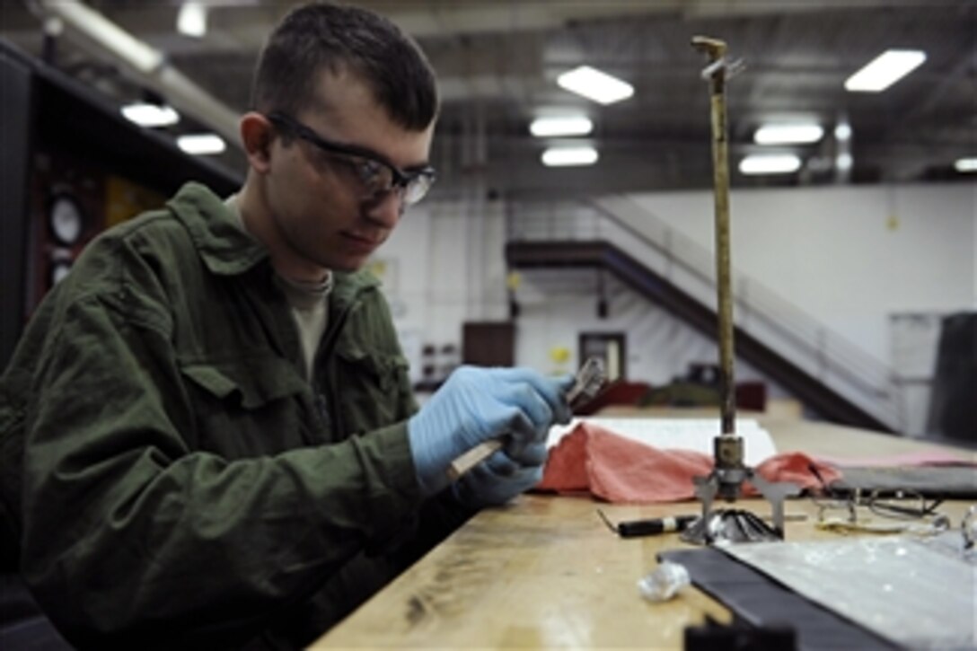 U.S. Air Force Airman 1st Class Robert Milburn, an aerospace ground equipment apprentice with the 28th Maintenance Squadron, uses a bristle brush to clean electrodes from a fuel-burning assembly at Ellsworth Air Force Base, S.D., on March 27, 2009.  The fuel-burning assembly is used to ignite the heat exchanger of new-generation heaters.  Maintenance personnel use the heaters to stay warm on the flight line.  