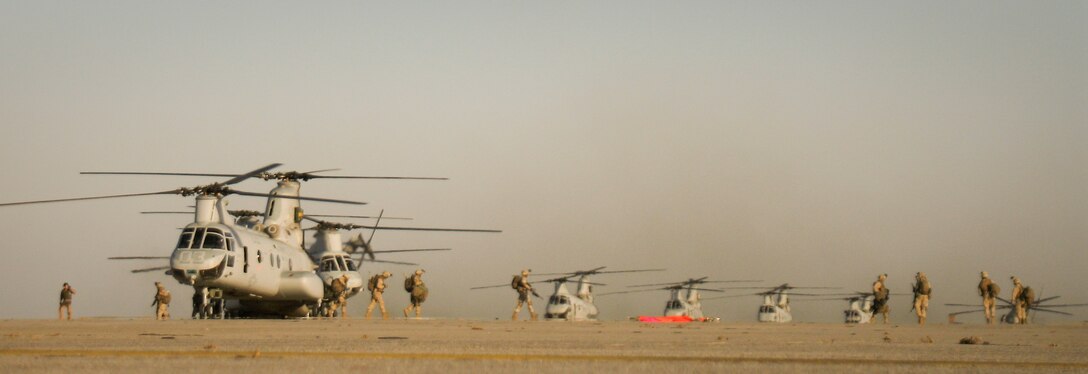 Marines with the 11th Marine Expeditionary Unit disembark transport helicopters lining up for fuel April 3 at Castle Airport. Twelve helicopters, eight transporting infantrymen, stopped here on a route to a simulated raid site during the MEU's recent air-ground task force exercise held at several California installations.