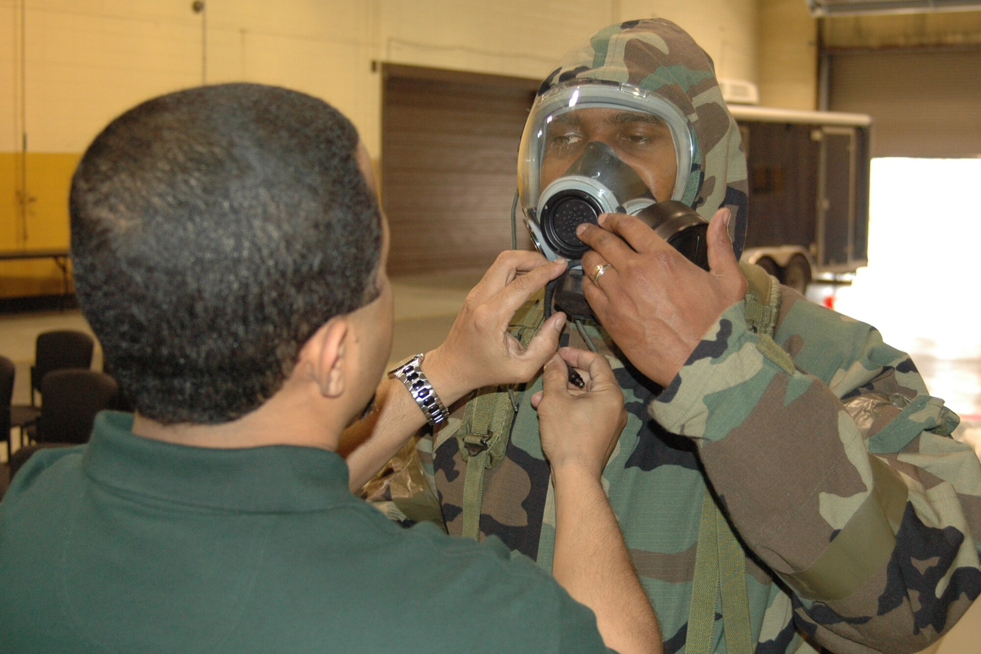 Mr. Andy McLean, Emergency Management chief, provides close attention to detail during a class instruction on the proper wear and fitting of a gas mask with Maj. Marcus Smith, 94th Logistics Readiness Squadron installation deployment officer.   (U.S. Air Force photo/Senior Airman Shaun Shenk) 