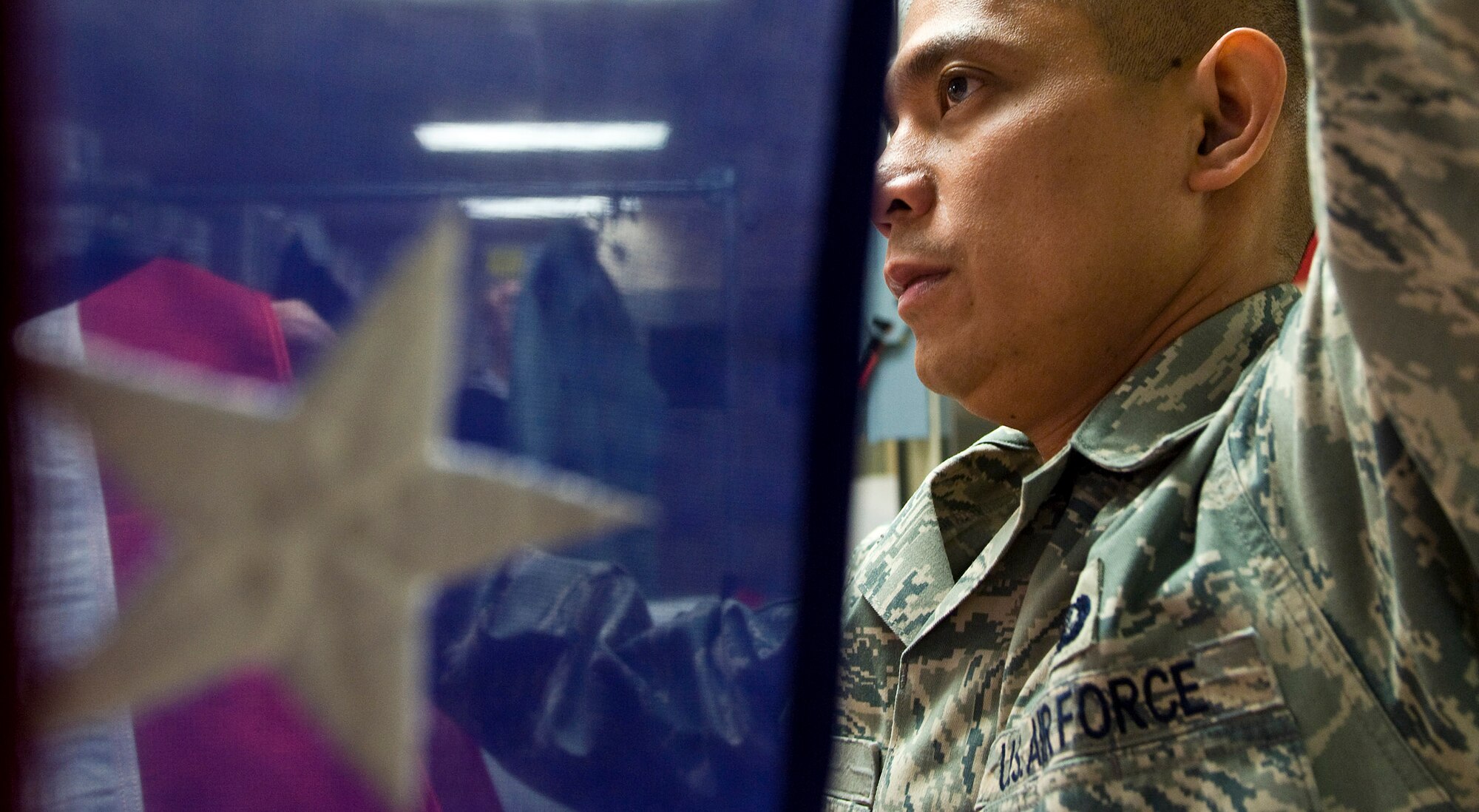 Tech. Sgt. Willard Rico feeds a U.S. flag into a pressing machine March 31 at the Charles C. Carson Center for Mortuary Affairs, Dover Air Force Base, Del.  The press irons the flags wrinkle free that will be placed over caskets during the dignified transfer of remains.  The center is the Defense Department's largest joint-service mortuary facility and the only one in the continental United States. Sergeant Rico is deployed from the 60th Force Support Squadron, Travis AFB, Calif.  (U.S. Air Force photo/Staff Sgt. Bennie J. Davis III)