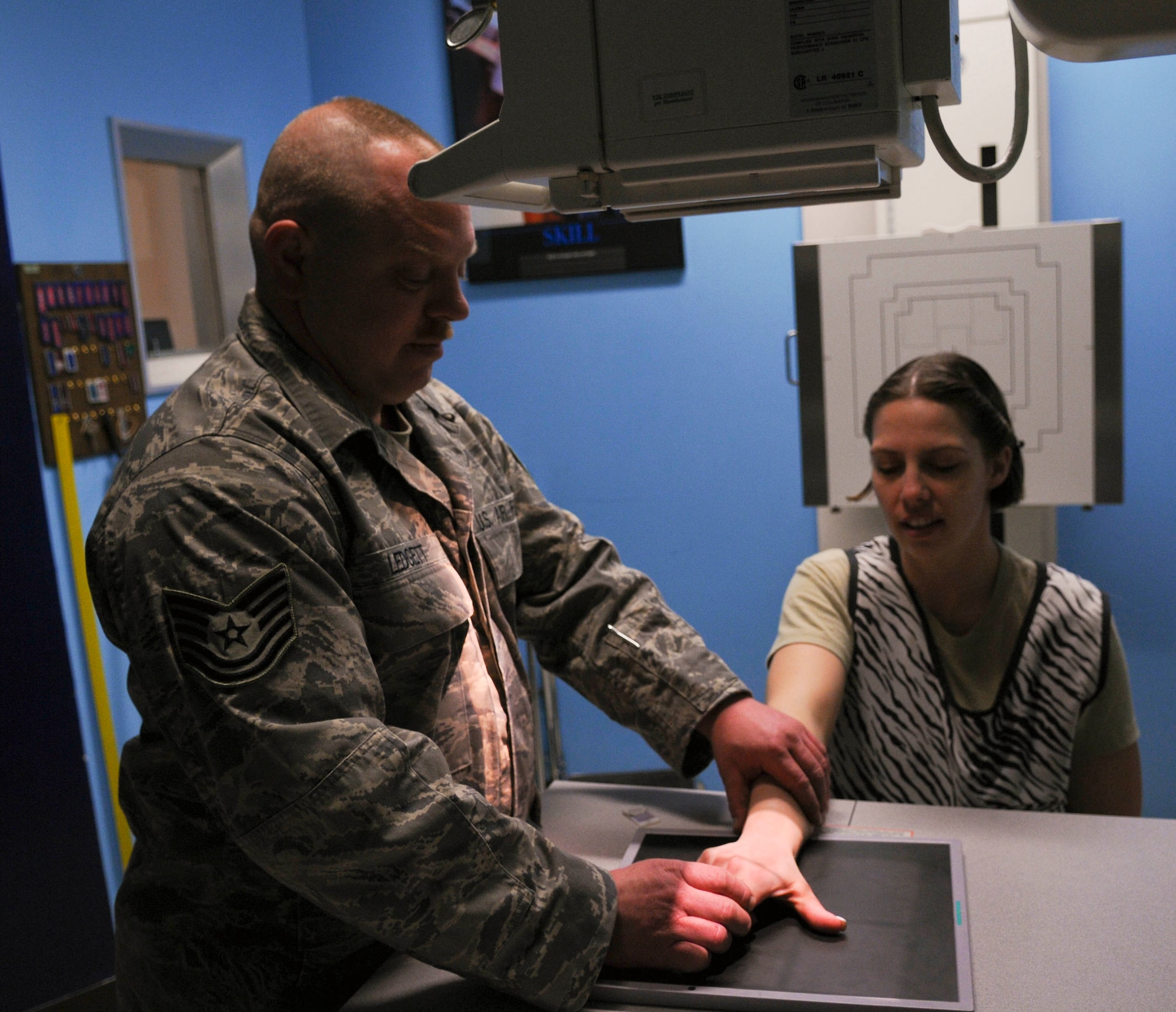 Tech. Sgts. Christopher Ledgett and Rebekah Virtue demonstrate how a hand is positioned using the anterior-posterior exposure April 2, 2009 Eielson Air Force Base, Alaska. This type of X-ray exposure means it will pass through the patient from front to back. Sergeant Ledgett is the NCO in charge of diagnostic imaging 354th Medical Group, and Sergeant Virtue is the NCO in charge of the pulmonary clinic 354th Medical Group. (U.S. Air Force photo/Airman 1st Class Laura Max)