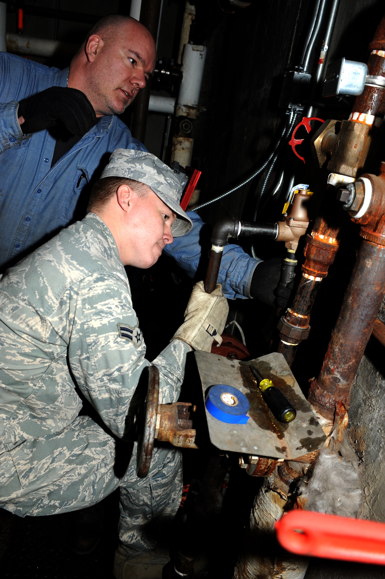 Allan Ford works alongside Airman 1st Class Joshua Bacon to tighten unions connecting the heat exchanger to the heating system. Ford works with the 3rd CES, and is a HVAC Maintenance Mechanic who has served as an Infantry Marine. Bacon is a 3rd CES HVAC 3131.(U.S. Air Force Photo by Airman Jack Sanders) 