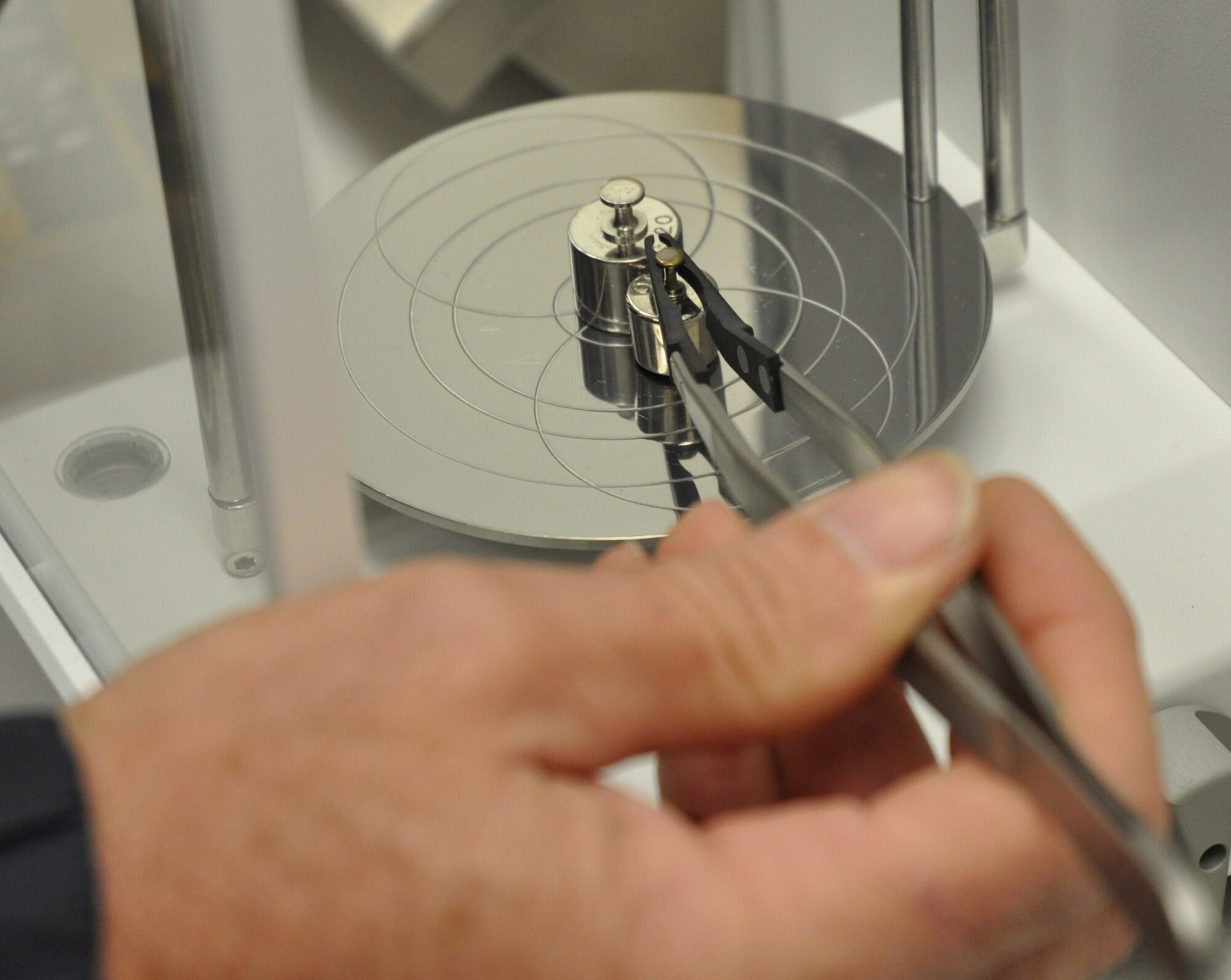 A 46th Maintenance Squadron Precision Measurement Equipment Laboratory technician at Eglin Air Force Base, Fla., verifies the scales that are used within the lab to calibrate equipment have maintained their proper accuracy. Gram weights have to be handled with tools or while wearing gloves to ensure they don't change in weight due to skin oils or small debris. (U.S. Air Force photo/Leslie Brown)