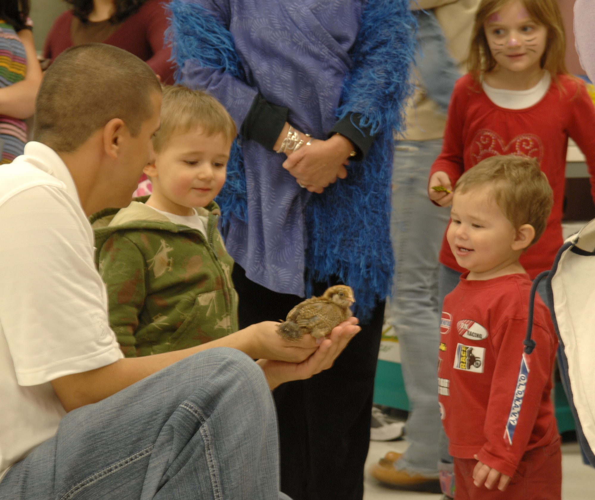 WHITEMAN AIR FORCE BASE, Mo. – Staff Sergeant Guiovany Venegas, 393rd Bomb Squadron (left), with his sons Nathan (center left) and Micah (right) while they enjoy a baby chick display at the block party in Whiteman’s youth center April 1.  The event, held at the base chapel and youth center, included free food, an indoor carnival, praise band and information fair.  (U.S. Air Force Photo by Staff Sgt. Bryan Vandersommen)