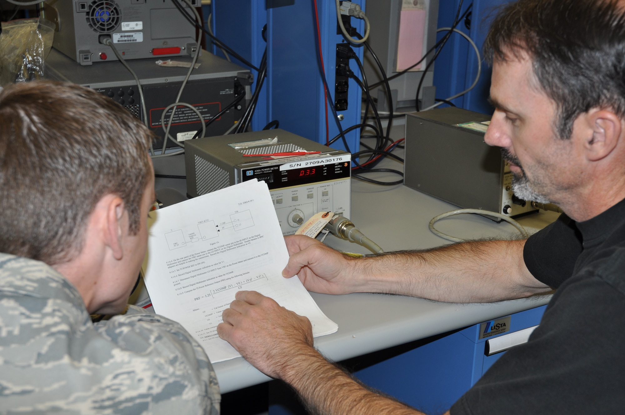 EGLIN AIR FORCE BASE, Fla. -- Eric Miller, right, assists Senior Airman Nathan Flannery, Precision Measurement Equipment Lab technicians, with research in a technical order procedure for calibrating a radio frequency generator.  PMEL is responsible for more than 22,000 pieces of equipment assigned to 406 accounts. (U.S. Air Force photo/Leslie Brown)