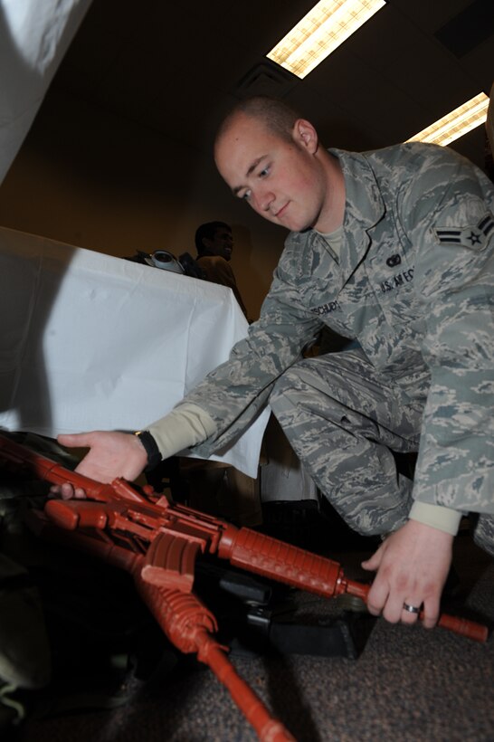Airman 1st Class Timothy Tschudy, 28th Security Forces Squadron combat arms apprentice, picks up a training weapon during the 2009 Cultural Expo in Rapid City, S.D., March 28. During the event Ellsworth Airmen demonstrated how to use equipment needed to accomplish the Air Force mission. (U.S. Air Force photo/Airman 1st Class Joshua J. Seybert)