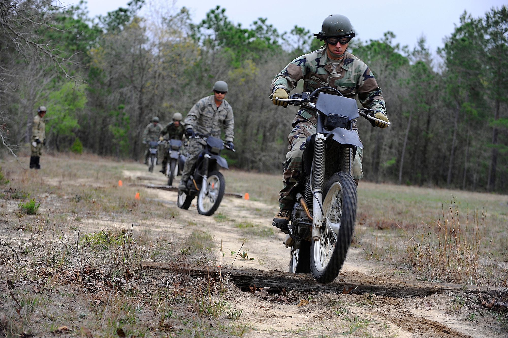 HURLBURT FIELD, Fla. -- Students from the 720th Special Tactics Training Squadron drive over small logs during a beginner level dirt bike course here, March 31. By accelerating slightly as the front tire hits the log at 90 degrees, the bike and rider safely maneuver over the obstacle. (U.S. Air Force photo/ Senior Airman Julianne Showalter)(RELEASED)