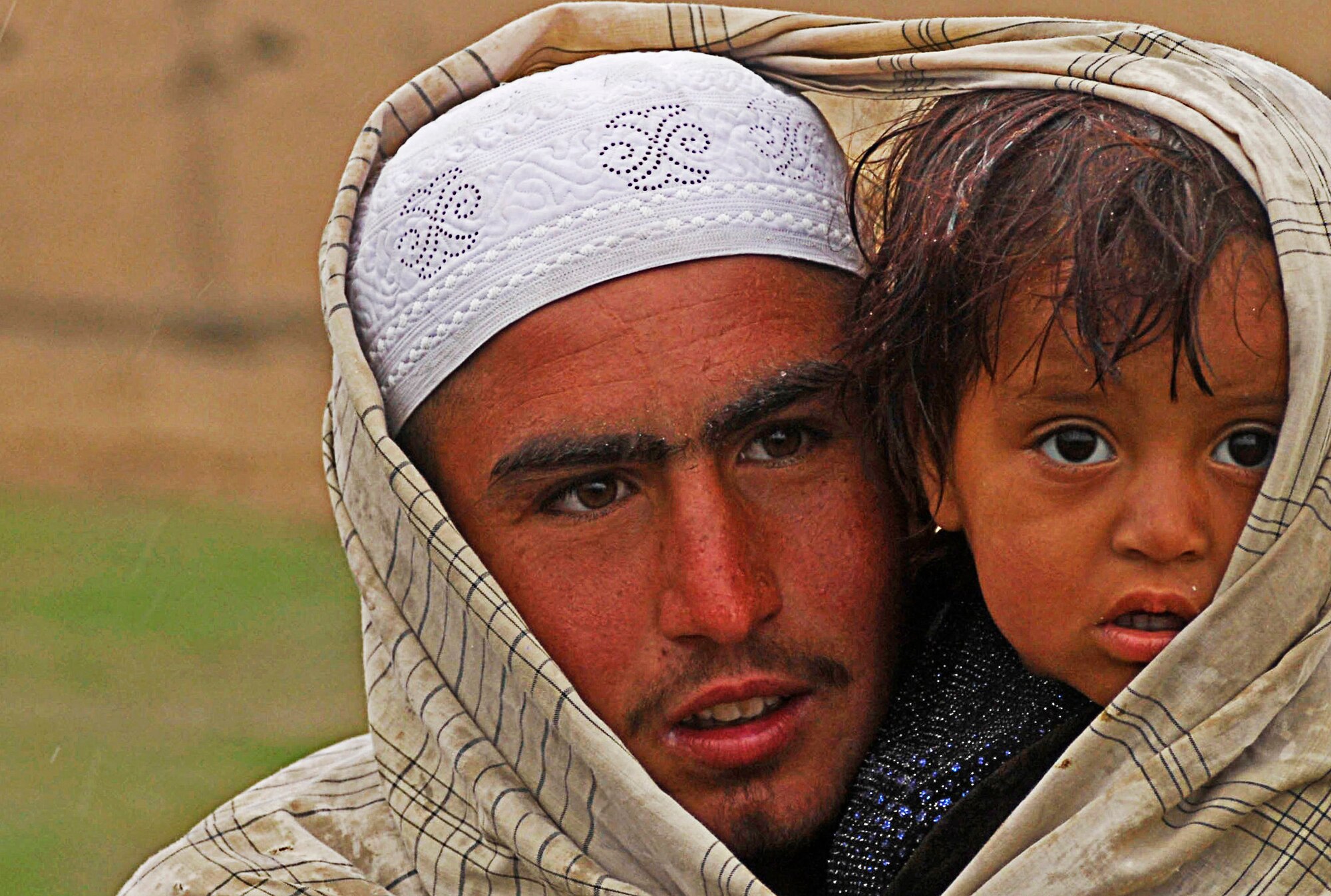 A brother and sister stand together in the rain as they wait to receive
clothes and shoes given by Air Force personnel from Bagram Air Field,
Afghanistan, April 1. (U.S. Air Force photo/ Senior Airman Erik Cardenas)(Released)
