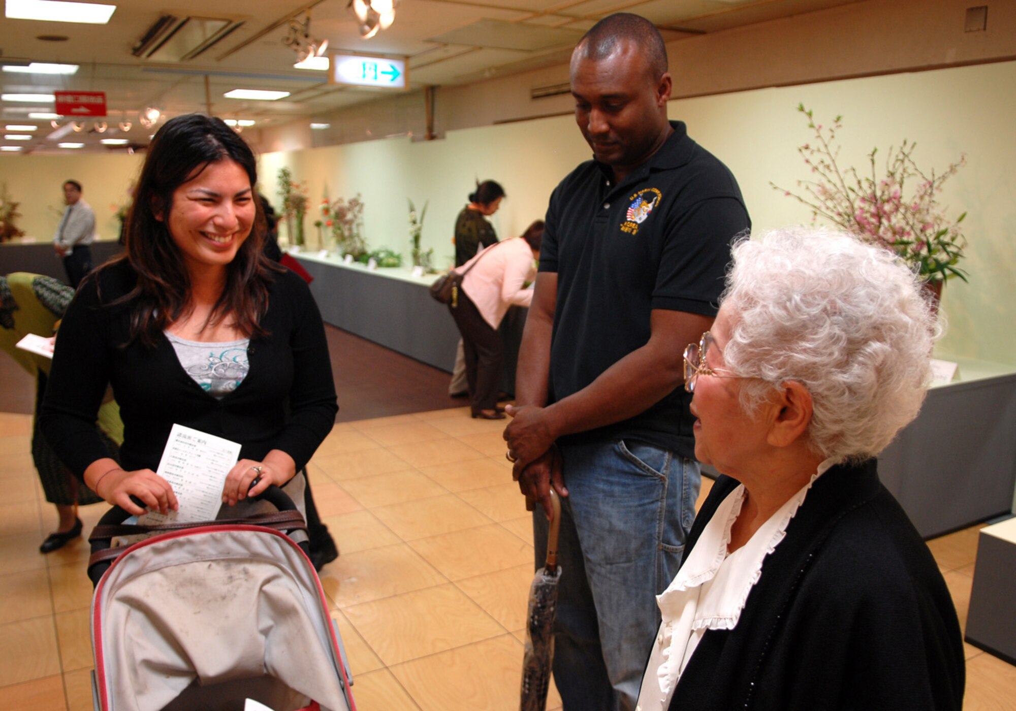 Keiko Nakajima Robbins (far right), founding member of Okinawaís Ikebana International since 1956 and Ikebana teacher at the Kadena Air Base USO, talks about her ikebana flower arrangement with her student Michiko Chiba Pratt and her husband Bry Pratt from Camp Kinser at the 51st Ikebana International Okinawa Chapter Charity 10 Flower Exhibition March 27-29.  Ms. Robbins teaches many people from different bases in Okinawa.  In October, the Ikebana International Okinawa Chapter and some students from the Kadena USO will go to the White House in Washington, D.C., for a flower demonstration and lecture. (U.S Air Force photo/Junko Kinjo)