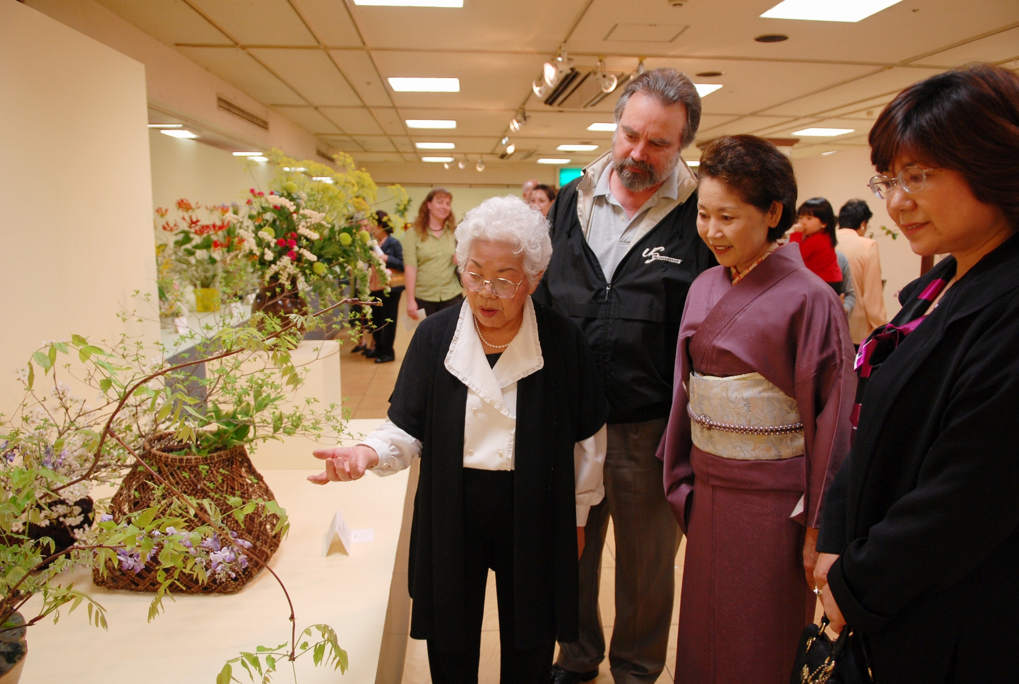 Keiko Nakajima Robbins (far left), founding member of Okinawaís Ikebana International since 1956 and Ikebana teacher at the Kadena Air Base USO, explains the essence of ikebana flower arrangement to Manly Slough, assistant manager of bakery on Camp Kinser; Naomi Zayasu, president of Ikebana International Okinawa Chapter 10; and Junko Nozaki, assistant base records manager for the 18th Communication Squadron, at the 51st Ikebana International Okinawa Chapter 10 Charity Flower Exhibition. The event was held March 27-29 at the Okinawa Mitsukoshi Department Store in Naha, Okinawa. In October, the Ikebana International Okinawa Chapter and some students from the Kadena USO will go to the White House in Washington, D.C., for a flower demonstration and lecture. (U.S Air Force photo/Junko Kinjo)