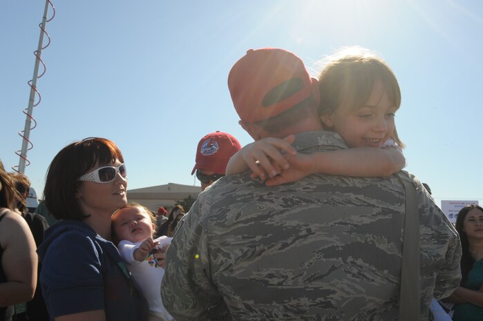 Tech. Sgt. Chris Hulles, 820th RED HORSE Squadron; holds his five-year old daughter, Leigh, while greeting his wife, Heather, who is holding their three-month old daughter, Kaleigh. This is Sergeant Hulles'  first time meeting his new daughter  after a seven-month deployment in Southwest Asia , April 6, Nellis Air Force Base, Nev.The mission of the 820th RHS is to provide the Air Force with a highly -mobile civil engineering capability in support of contingency and special operations worldwide. (U.S. Air Force photo by Senior Airman Nadine Y. Barclay)  (RELEASED)