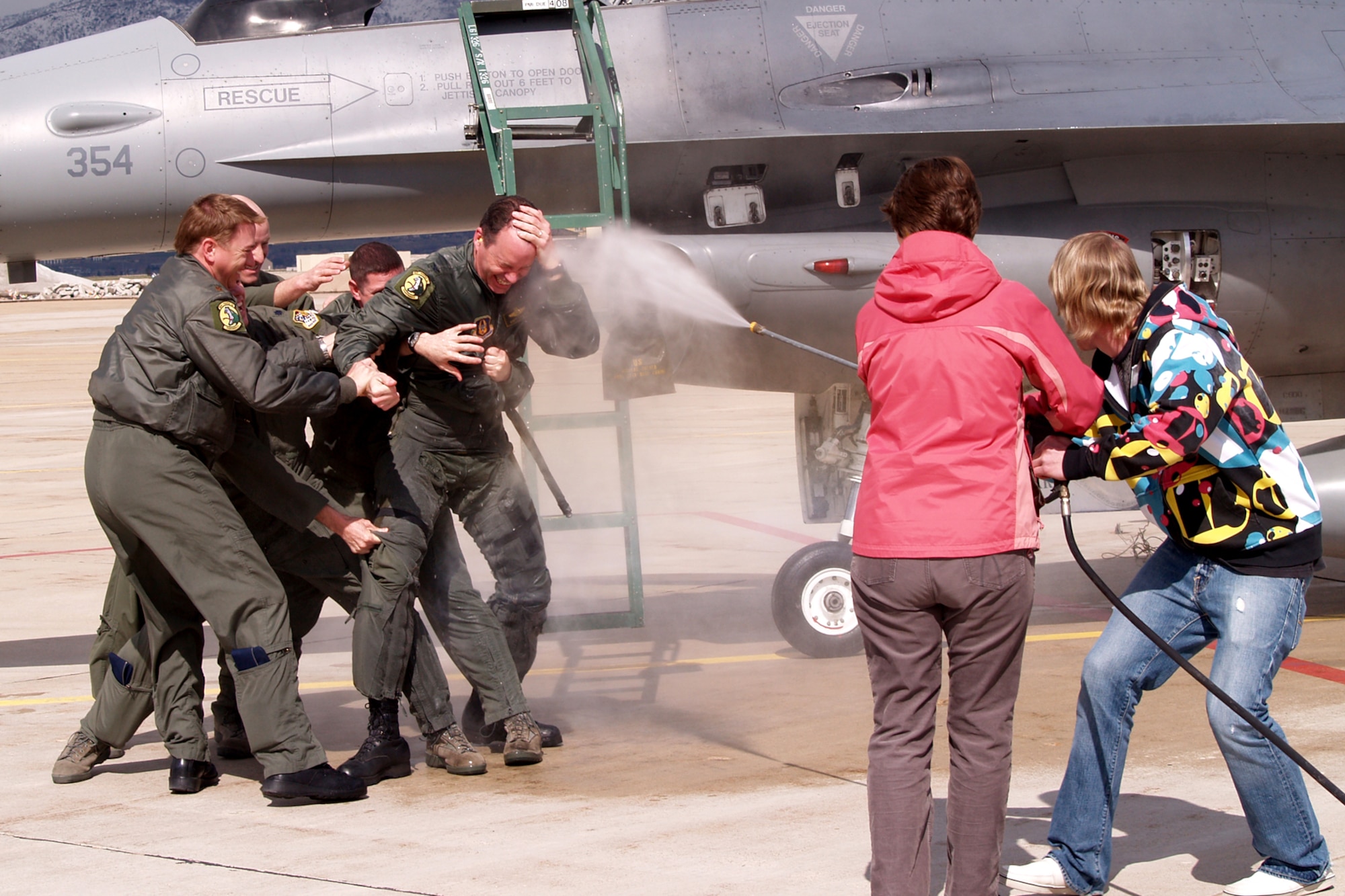 Fellow pilots hold back Col. Andrew R. "Hoops" Larson, Vice Commander of the 419th Fighter Wing, as his sister and son pummel him with a stream of water -- part of the "fini" flight tradition. Colonel Larson flew his last flight in an F-16 with the Air Force Reserve Apr. 4. (U.S. Air Force photo/Senior Airman Brandon Craig)