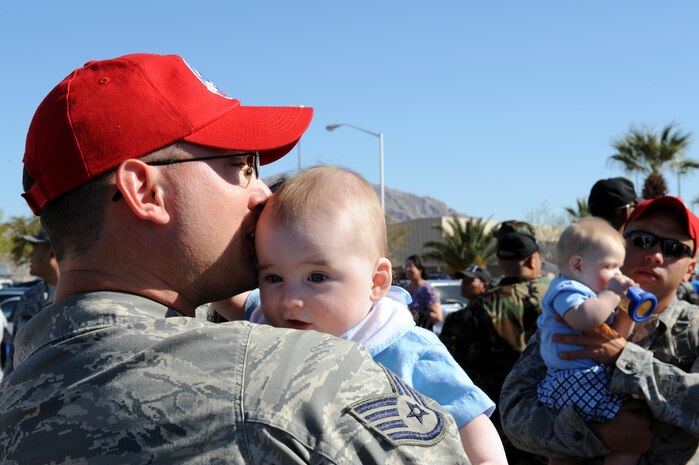 Staff Sgt. Jonathan Kannenberg from the 820th RED HORSE Squadron holds his six month old son, Zackery, upon his arrival home after a seven-month deployment in Southwest Asia, April 6, Nellis Air Force Base, Nev. RED HORSE squadrons provide the Air Force with a highly-mobile civil engineering capability in support of the contingency and special operations worldwide.(U.S. Air Force photo by Airman 1st Class Brett Clashman/Released)