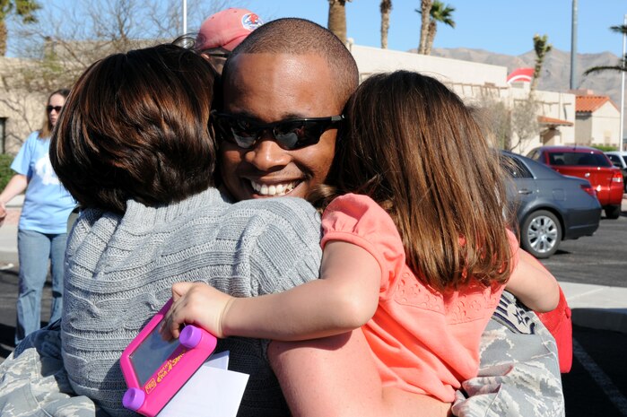 Staff Sgt. Frederick Battle from the 820th RED HORSE Squadron is greeted by his wife, Jennifer, and his daughter, Alana, upon his arrival home after a seven-month deployment in Southwest Asia, April 6, Nellis Air Force Base, Nev. RED HORSE squadrons provide the Air Force with a highly-mobile civil engineering capability in support of the contingency and special operations worldwide.(U.S. Air Force photo by Airman 1st Class Brett Clashman/Released)