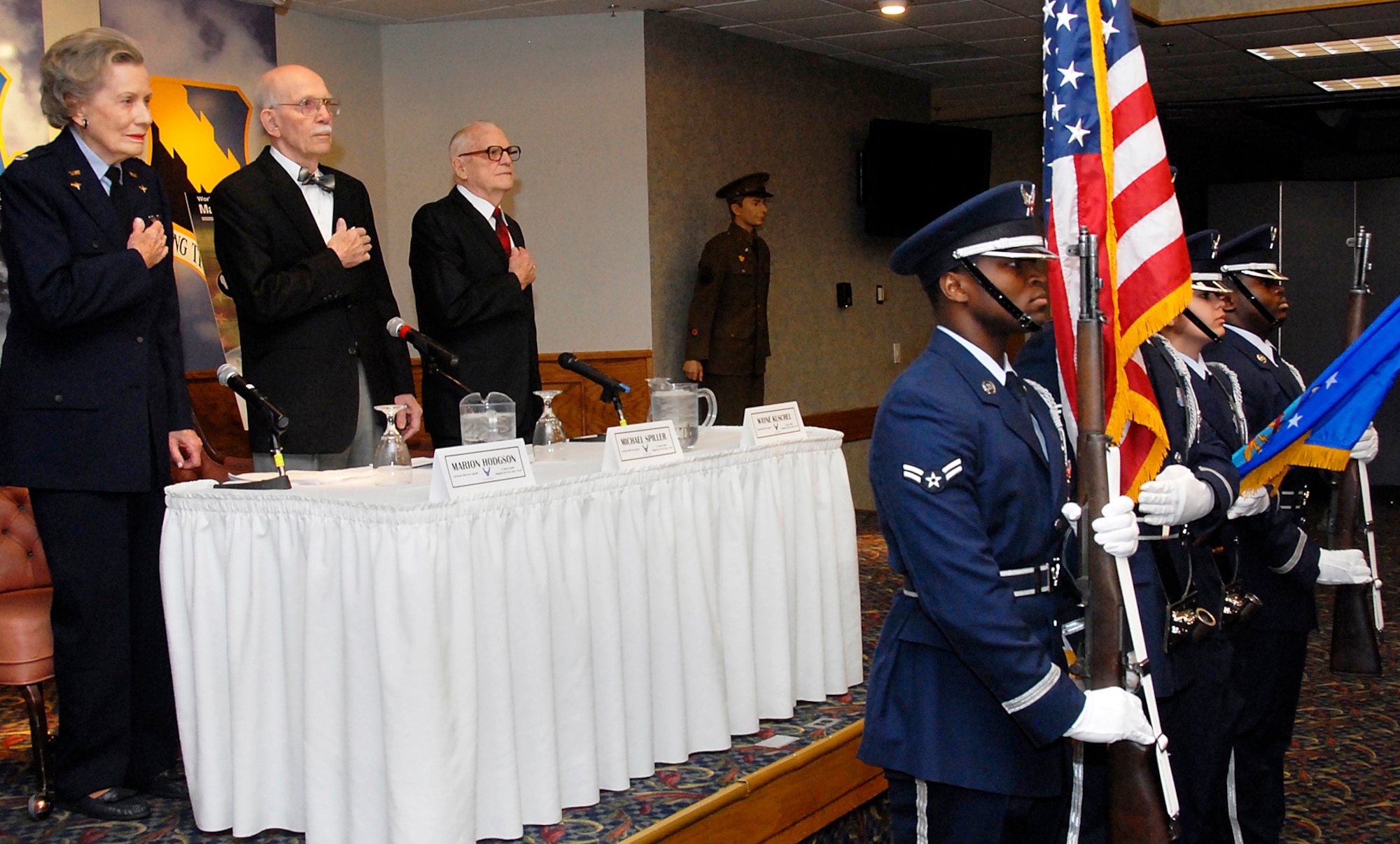 World War II pilots (from left on stage) Marion Stegeman Hodgson, Michael Spiller and Wayne Kuschel pay respect to the national anthem March 31 during "Lunch with the Legends" at the base club at Sheppard Air Force Base, Texas. The three shared their wartime experiences. (U.S. Air Force photo/Mike Litteken)