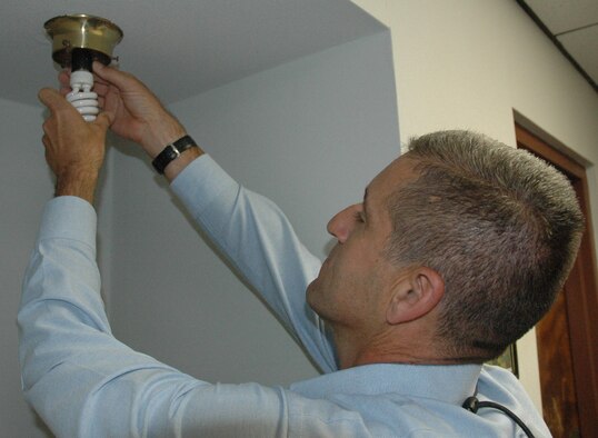 Michael MacMullin, 325th Operations Support Squadron F-15 quality assurance representative, replaces an incandescent light bulb with an Energy Star qualified model during "Operation Change Out."  (U.S. Air Force photo by Senior Airman Anthony J. Hyatt)