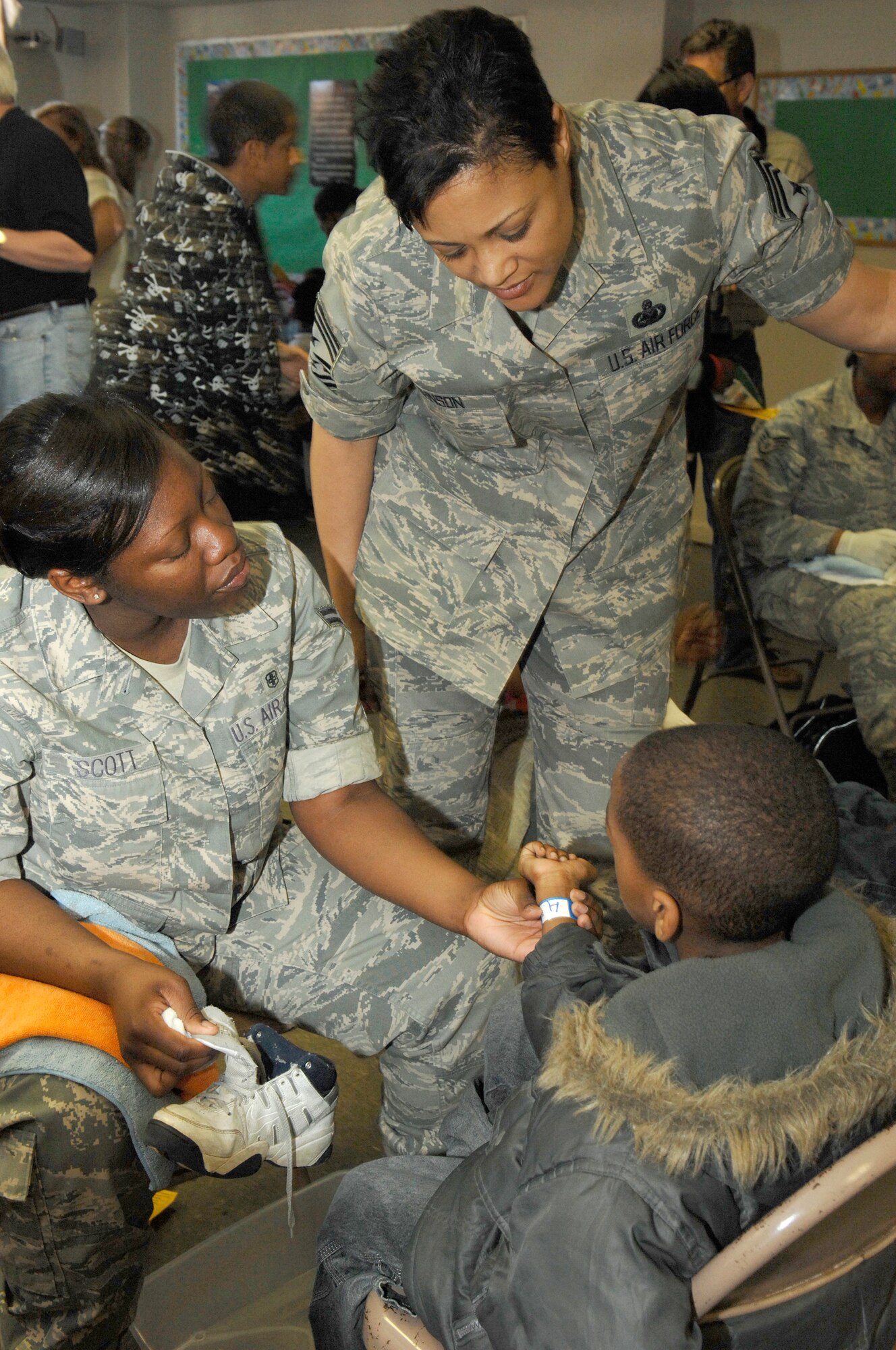 Chief Master Sgt. Robin Johnson, 11th Wing Command Chief Master Sergeant, and Airman 1st Class Amanda Scott, 579th Medical Group, help a child get new shoes and socks during a community event April 4.  More than 1,000 pairs of shoes were handed out to D.C. children during the event, sponsored by Samaritan’s Feet. (U.S. Air Force photo by Staff Sgt. Dan DeCook)