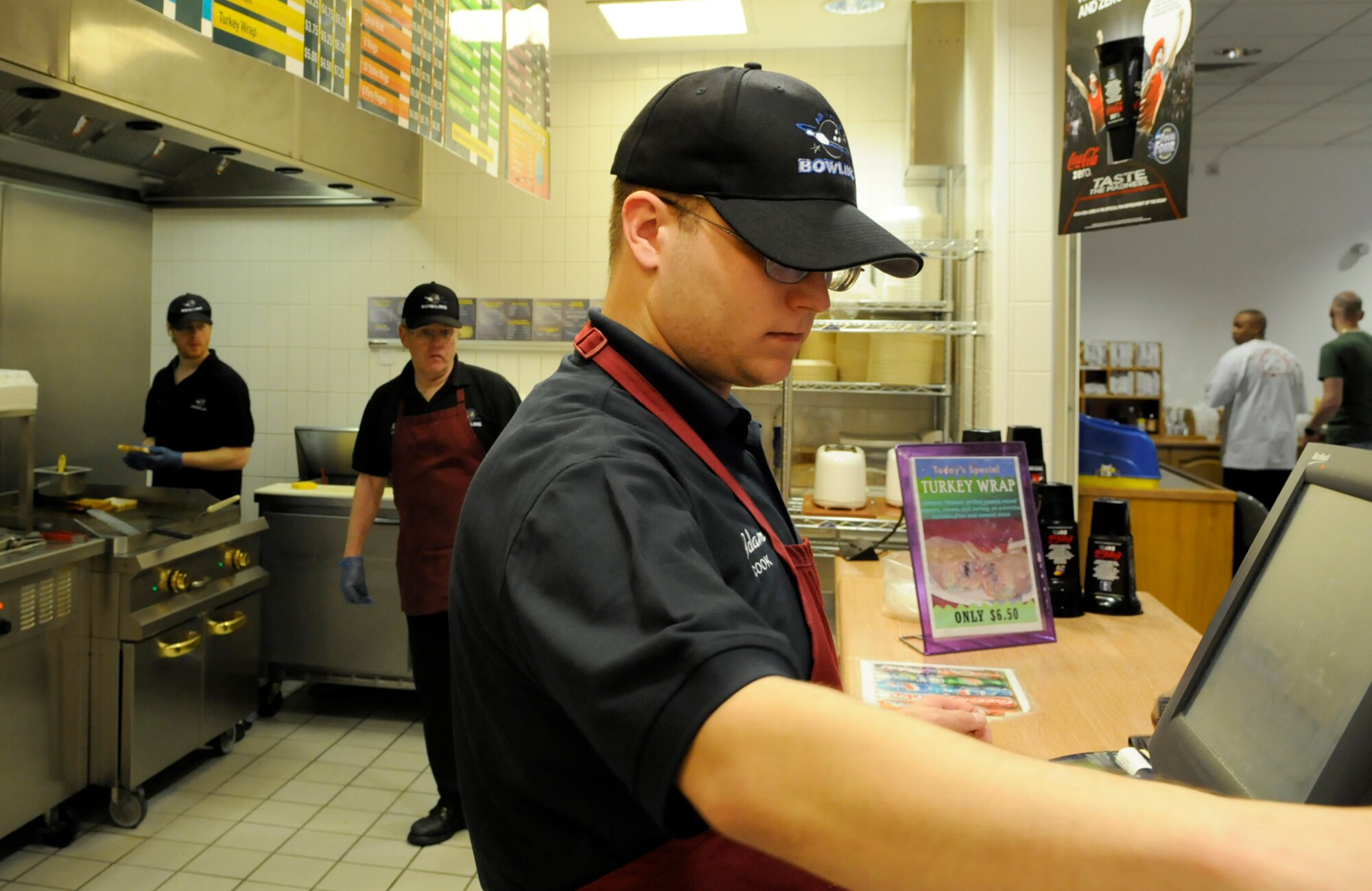 Adam Williams, a cook at the RAF Mildenhall bowling center, takes orders from customers April 3 with fellow cooks Robert Ashley (center) and Mitchell Gerber (left.)  The cooks provide one of the many services that contributed to the bowling center being named best in the Air Force.  (U.S. Air Force photo by Senior Airman Christopher L. Ingersoll)
