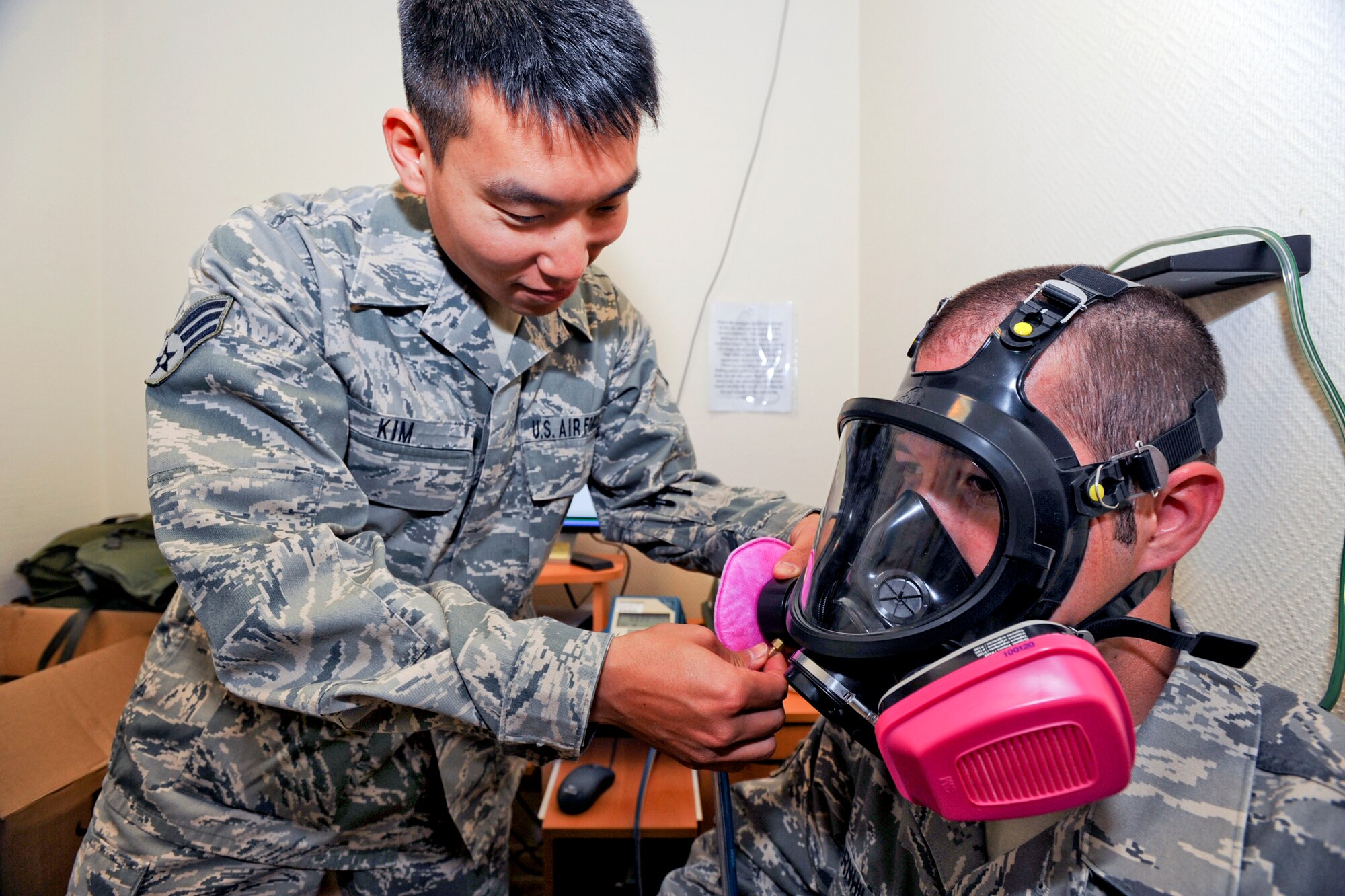 Senior Airman Andrew Kim, a bio-environmental engineering technician with the 379th Medical Group, tightens Senior Airman Jonathan Barnhill's gas mask prior to a fit test, April 7, 2009, in an undisclosed location in Southwest Asia.  Airman Barnhill is assigned to the 379th Expeditionary Maintenance Squadron and his gas mask must be periodically tested for fit to ensure a good seal is obtained when wearing it.  Airman Kim is native to Walnut Calif. and is deployed from Keesler Air Force Base, Miss. and Airman Barnhill is native to Melbourne Fla. and is deployed from Langley Air Force Base, Va. in support of Operations Iraqi and Enduring Freedom and Combined Joint Task Force - Horn of Africa.  (U.S. Air Force Photo by Staff Sgt. Joshua Garcia/released)