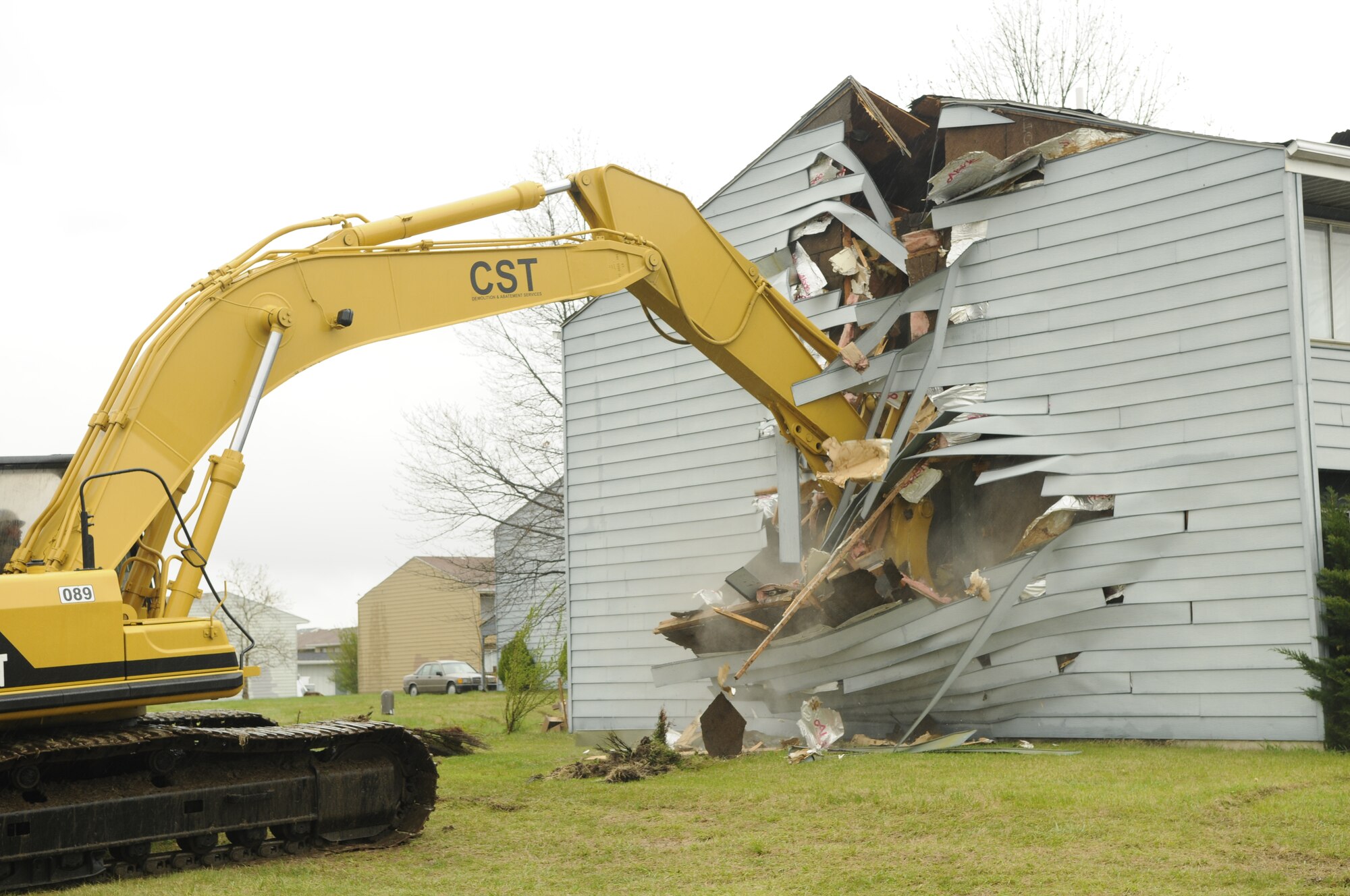 11th Wing Commander Col. Jon A. Roop, using an excavator, demolishes the side of the first home that was built in the old Rickenbacker South neighborhood April 3 at the BLB Privatized Housing groundbreaking ceremony. The ceremony was held to commence the demolition of old homes and the construction of new homes there. (U.S. Air Force photo by Staff Sgt. Raymond Mills)