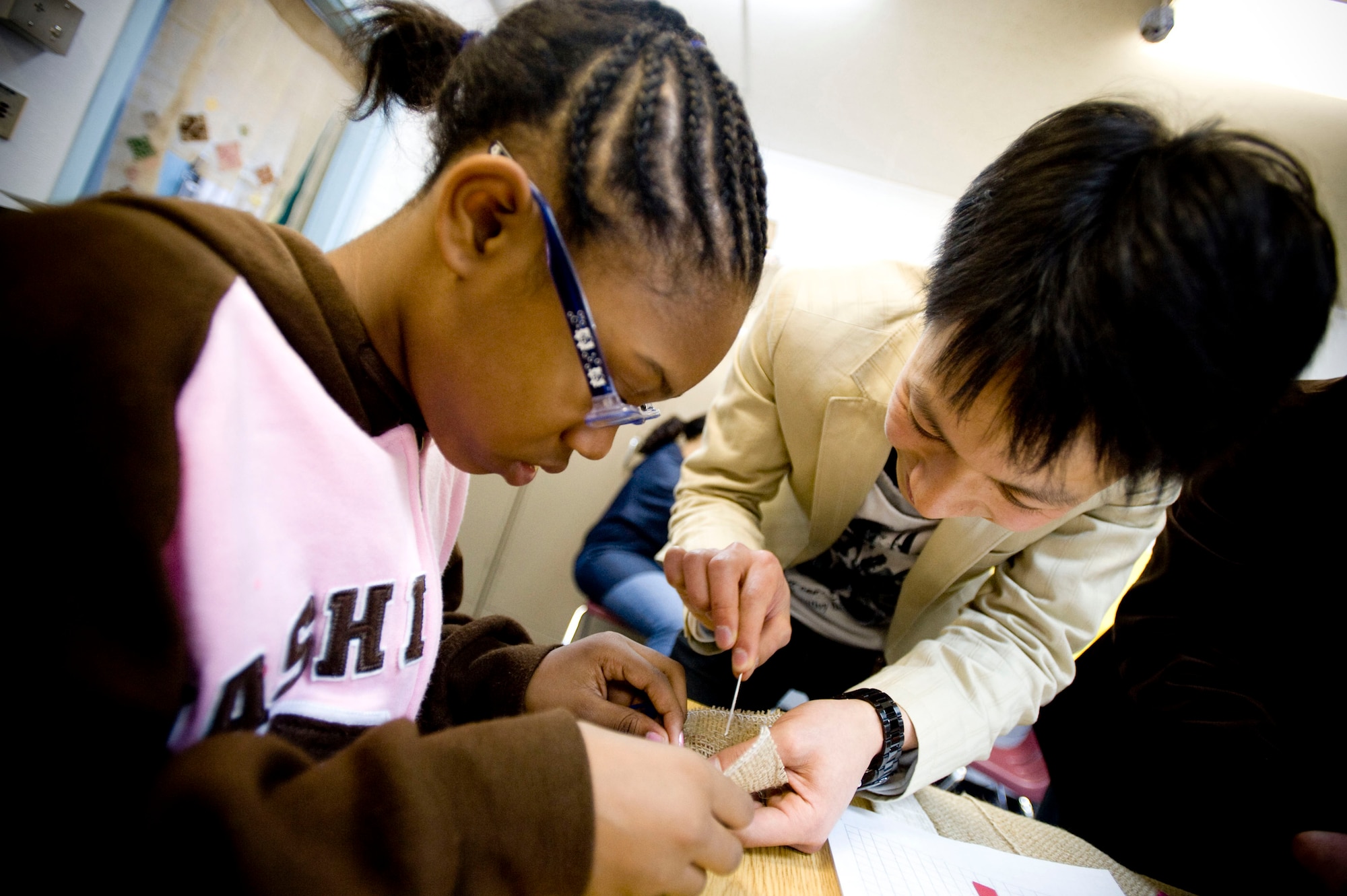 MISAWA AIR BASE, Japan -- Abe Terumasa (right) shows Tiarra Erby how to perform the next stitch in her kogin embroidery during Japan Day April 4, 2009. Kogin embroidery is a hand-stitching technique originating in Northern Japan to re-enforce fabric to withstand the cold, but has grown into an art form that still survives today. (U.S. Air Force photo by Staff Sgt. Samuel Morse)