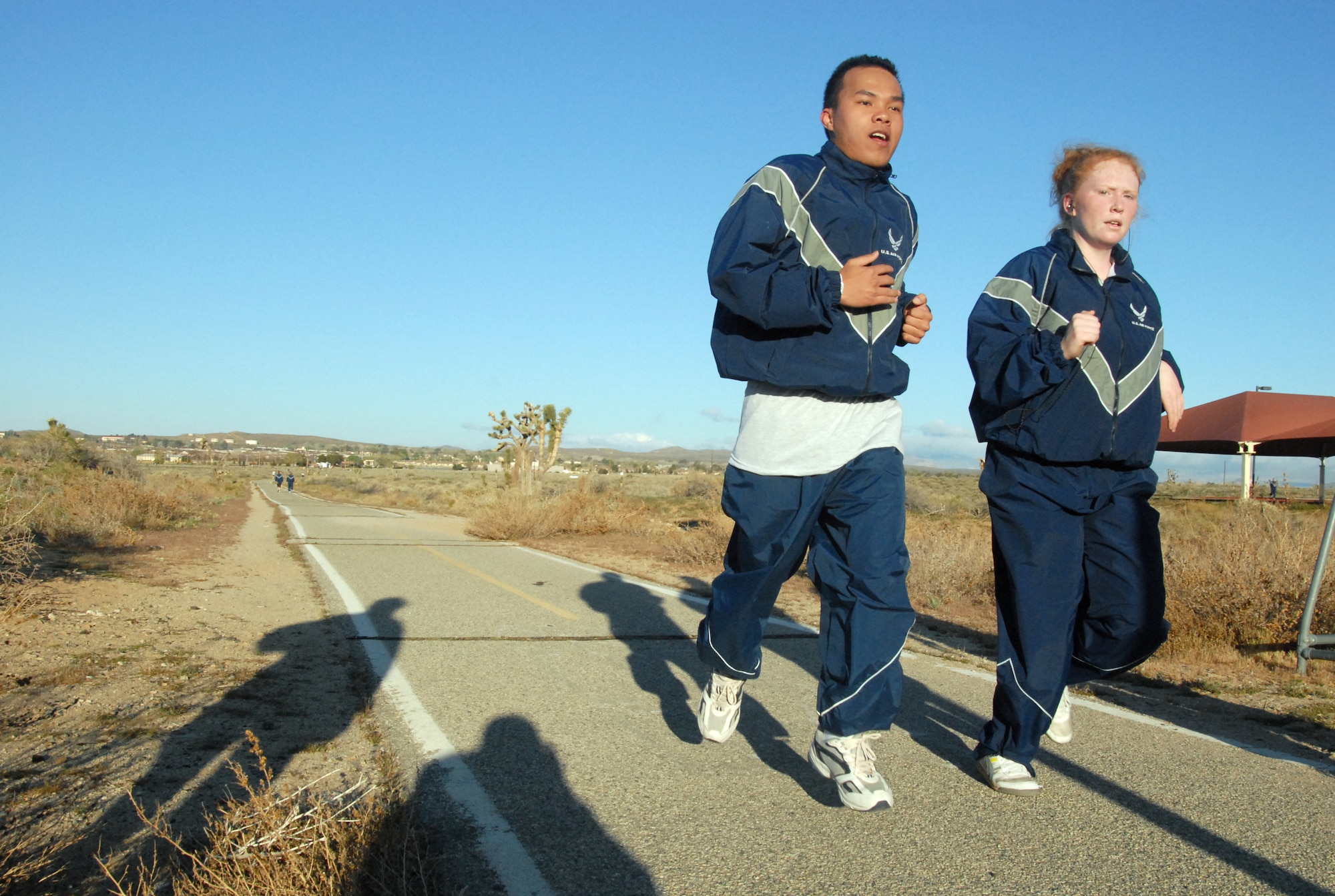 Airman 1st Class Jose Aurellano and Airman Lauren Birk, both from the 95th Force Support Squadron, run at the Rosburg Fitness Center track as part of their squadron physical training. (U.S. Air Force photo/Senior Airman Julius Delos Reyes)