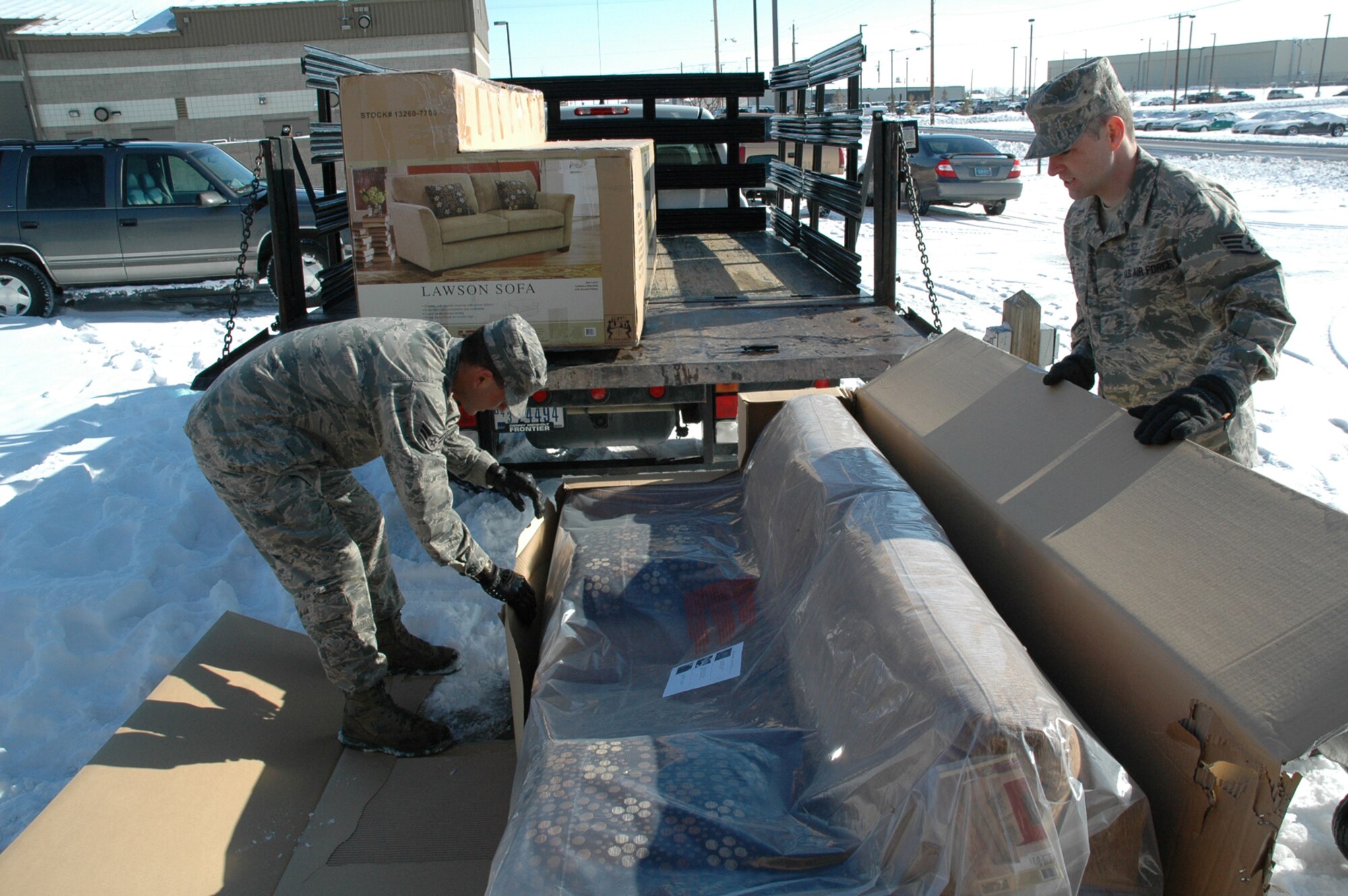 Airman 1st Class Anthony Melendez, 341st Missile Maintenance Squadron, electro-mechanical team member, and Staff Sgt. David Boice, 341st Missile Wing chaplain assistant, unpack a new couch at the Detour Airmen's center March 30. The renovated Detour reopened April 2. New furniture , televisions and video players were paid for by Cascade County DUI Task Force, the Enforcing Underage Drinking Laws grant, and several base organizations. (U.S. Air Force photo/Senior Airman Dillon White)