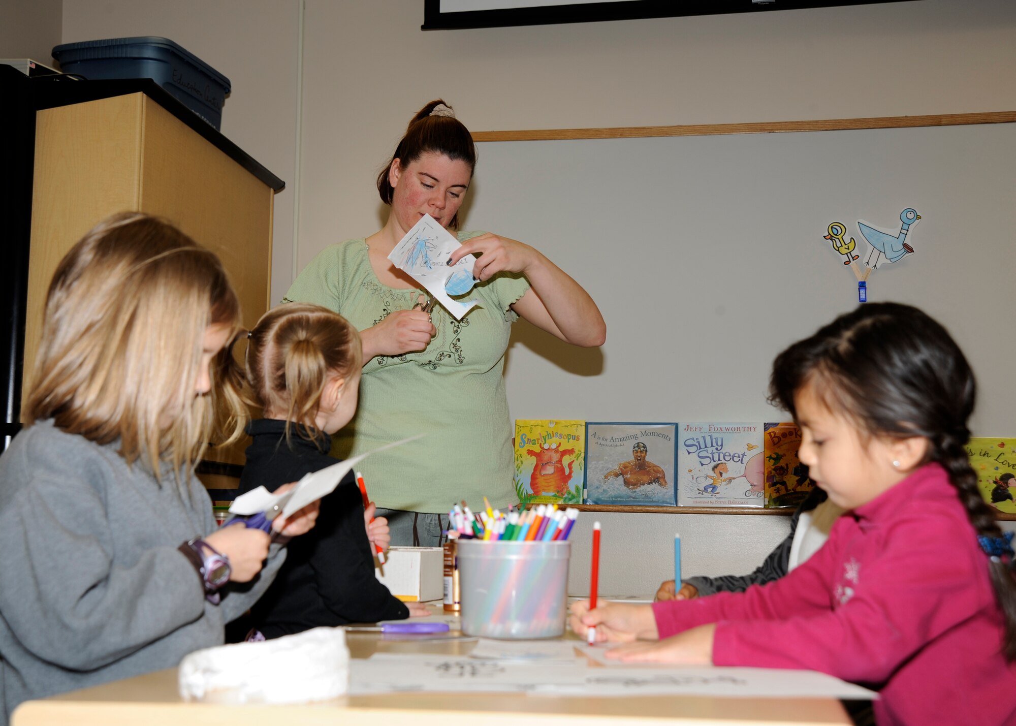 MCCONNELL AIR FORCE BASE, Kan. --  Gretchen Huber helps Lana Stalter, 5, Brynlee Lloyd, 3, Isaiah Duhart, 4, Alexa Lawrence, four, make doorknob hangers during preschool story time at the Robert J. Dole Community Center, April 7. The program is provided for children by the base library once a week and consists of reading, playing, and crafting segments. (Photo by Airman Justin Shelton) 