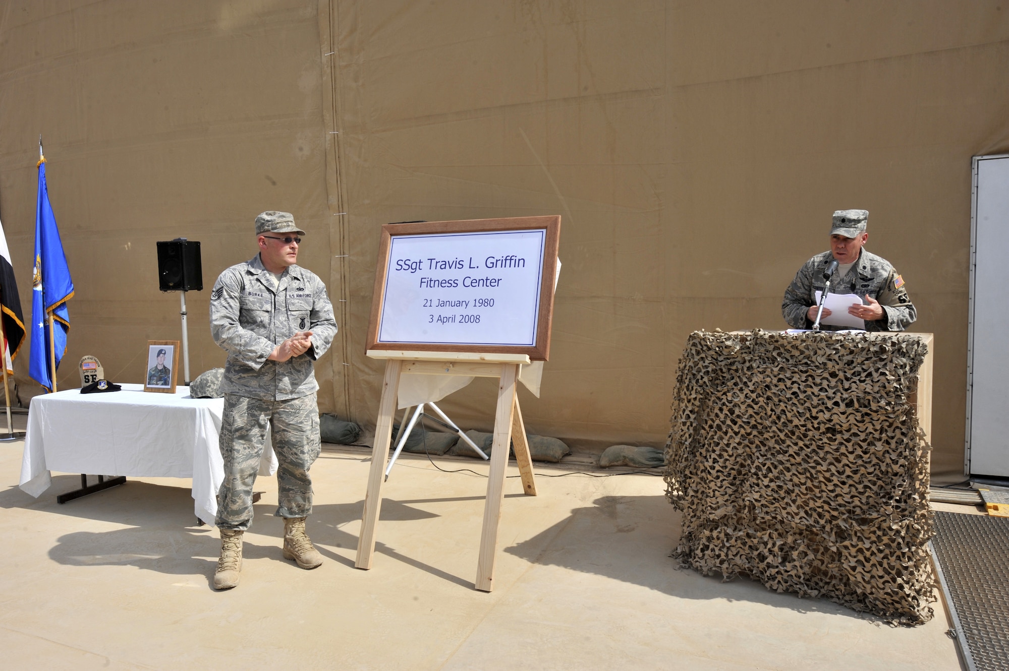 SATHER AIR BASE, Iraq – Staff Sgt. Ryan Burke, left, claps after unveiling a sign while Lt. Col. Steven Painter speaks to a crowd during a dedication ceremony here April 3 honoring a fallen security forces member. More than 75 447th Expeditionary Security Forces members and fellow Airmen attended the ceremony, during which Sather Airmen renamed the base fitness center after Staff Sergeant Travis Griffin, who lost his life April 3, 2008, while on patrol in Baghdad, Iraq. Colonel Painter is the 447th Expeditionary Security Forces commander here. Sergeant Burke was Sergeant Griffin’s friend and attended the ceremony from Balad Air Base, Iraq, where he is deployed as a 532nd ESFS member. (U.S. Air Force photo by Staff Sgt. Amanda Currier)