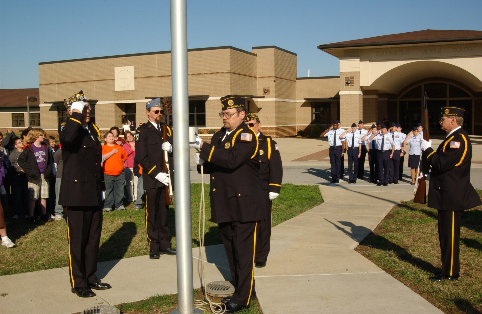 SCOTT AIR FORCE BASE, Ill. --Members of Post 365 American Legion and Sons of Veterans from Collinsville, raise the American flag outside of Collinsville Middle School April 3, with members of the 375th Logistics Readiness Squadron saluting in the background. The American flag was flown recently at the 330the Transportation Battalion Headquarters in Balad, Iraq and sent to the 375th LRS who donated it to the school. (U.S. Air Force photo/Airman 1st Class Amber Kelly-Woodward)