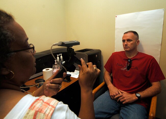 Army Sgt. Maj. Roger Dangerfield has his photograph taken for the Defense Biometric Identification System at the visitor's center on Charleston AFB April 6. Several pieces of information are obtained from individuals for DBIDS including pictures and fingerprints for additional means of identification. Sergeant Dangerfield is with the 218th Maneuver Enhancement Brigade and Ms. Garret is a security clerk with the 437th Security Forces Squadron. (U.S. Air Force photo/Senior Airman Timothy Taylor)