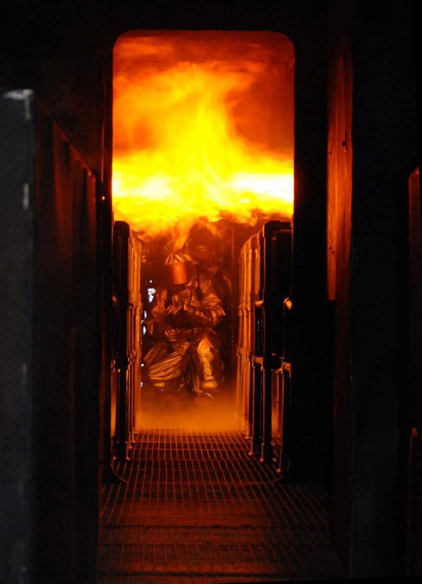 Senior Airman Bradley Fear leads the charge against a fuselage engulfed in flames at the Woensdrecht Firefighting Training Facility in the Netherlands. Airman Fear and other members of the 309th Airlift Squadron from Chievres Air Base, Belgium, trained on the simulator. (U.S. Air Force photo) 
