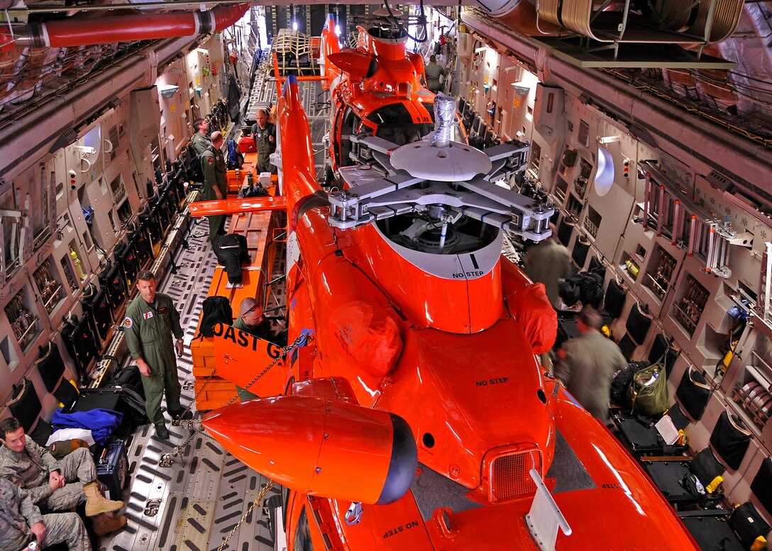 A C-17 Globemaster III aircrew from the 315th Airlift Wing, Charleston AFB, S.C. loads two Coast Guard helicopters in preparation for flight.  The helicopters are being delivered to Central America. (Air Force photo/Captain Chett Collier)