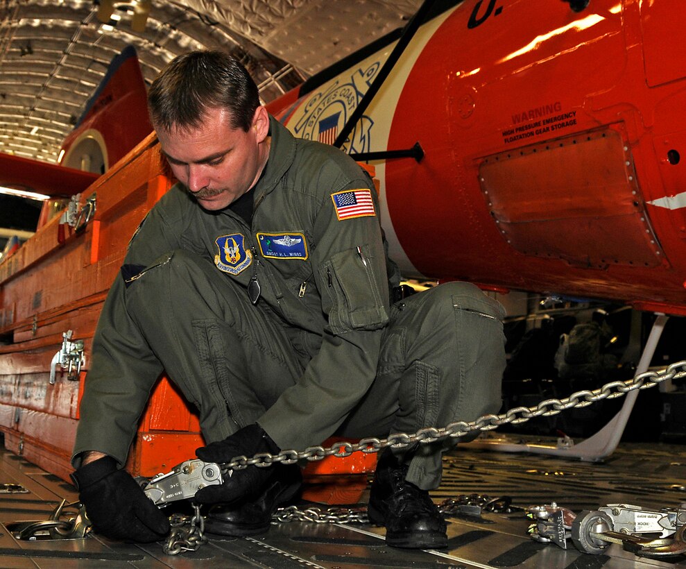 Senior Master Sergeant H.L. Wiggs, a reservist with the 701st Airlift Squadron, Charleston AFB, S.C.  helps secure a Coast Guard helicopter aboard a Charleston C-17Globemaster III, The helicopter is being delivered to Central America. (Air Force photo/Captain Chett Collier)