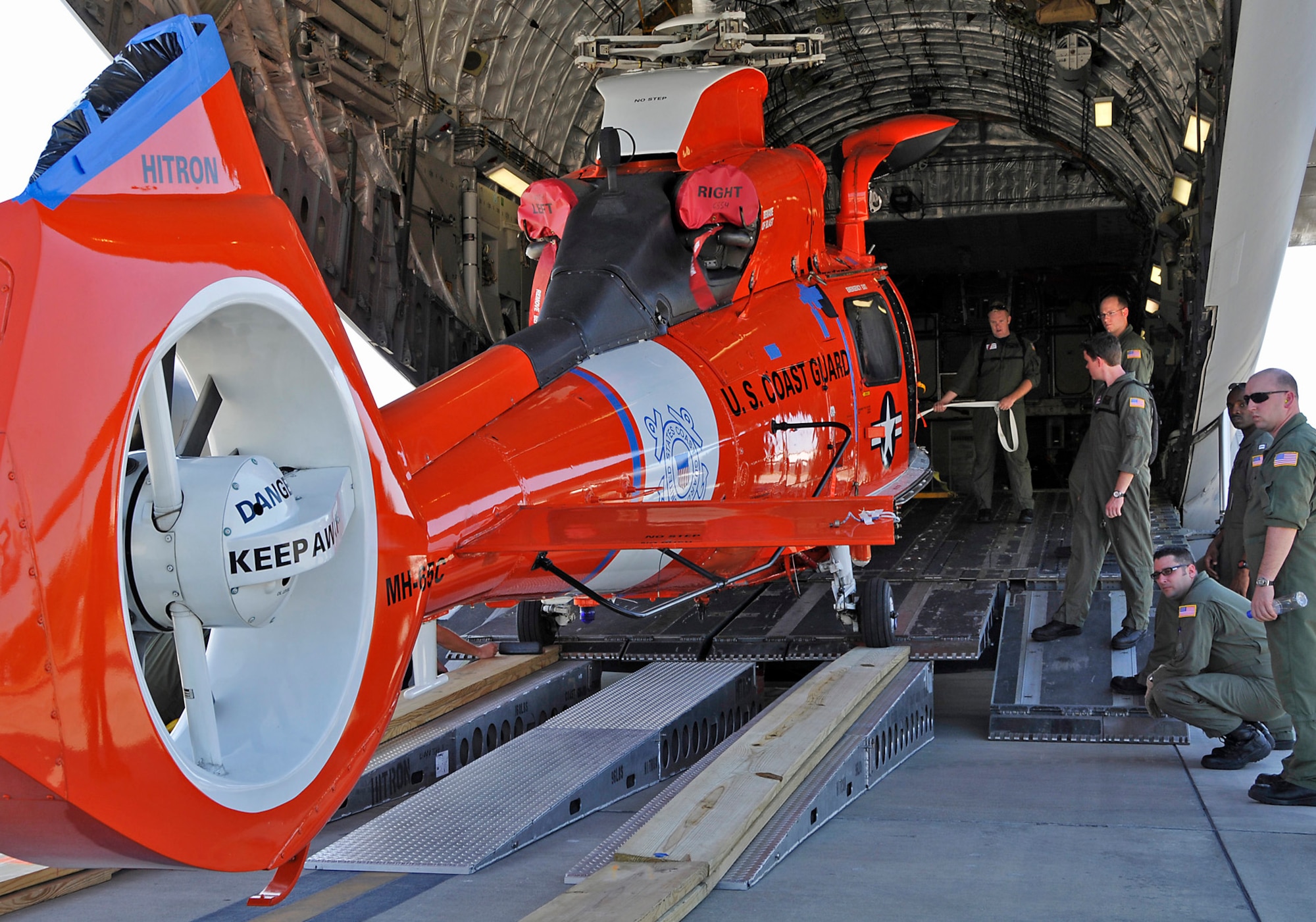 A C-17 Globemaster III crew from Charleston AFB, S.C. loads a Coast Guard helicopter in preparation for flight.  The helicopter is being delivered to Central America. (Air Force photo/Captain Chett Collier)