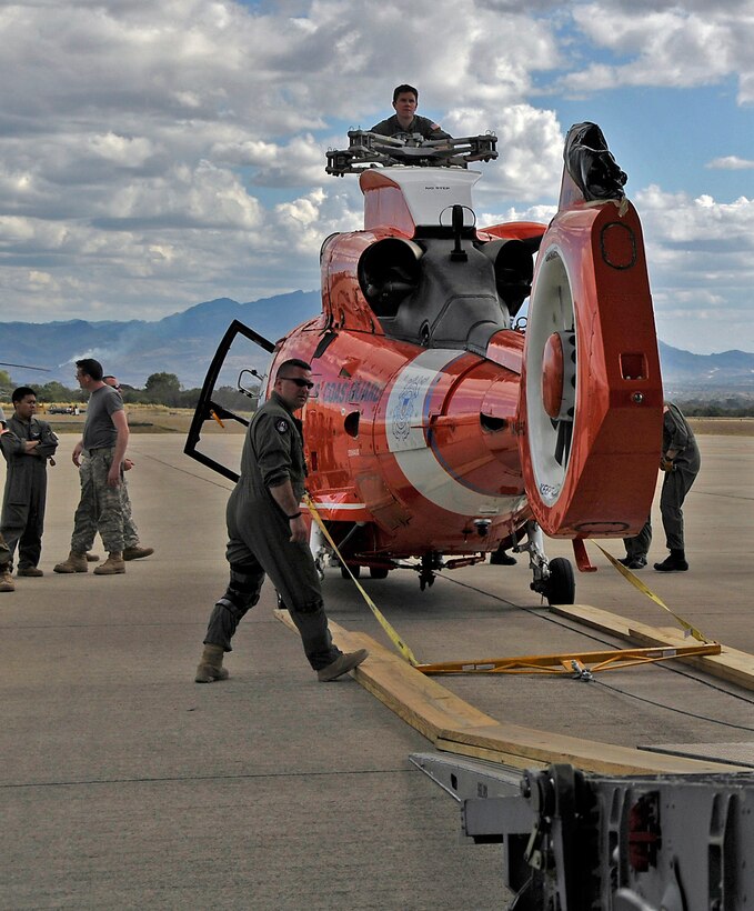 An aircrew from Charleston AFB, S.C. prepares to load a Coast Guard helicopter aboard a C-17 Globemaster III.  The helicopter is being delivered to Central America.  (Air Force photo/Captain Chett Collier)