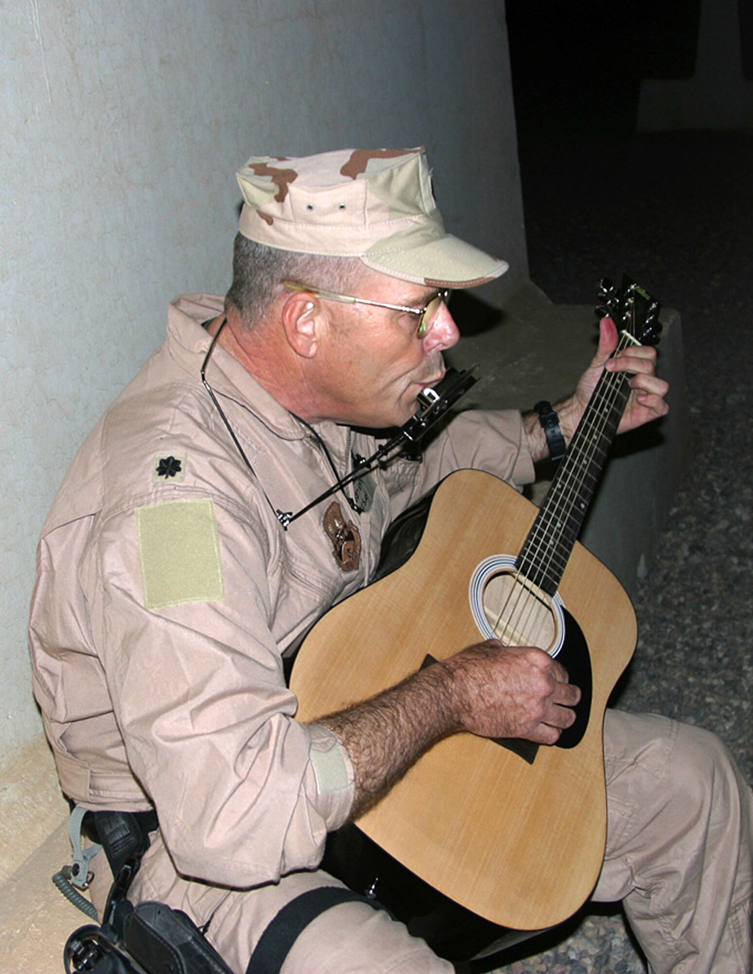 CAMP BUCCA, Iraq -- Lt. Col. Gregory Laffitte, 887th Expeditionary Security Forces Squadron physician assistant, plays his guitar and harmonica next a bunker off-duty Feb. 4. Colonel Laffitte often plays outside the post chapel and will sometimes play for the Iraqi children waiting to see their family members at the Theater Internment Facility's visitation center. (U.S. Army photo by Maj. Jason Fetterolf)