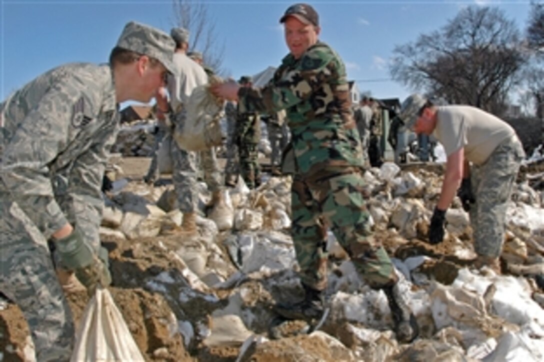 U.S. Air Force Staff Sgt. Bryan Hensel, left and Tech. Sgt. Les Ressler, center, pass sandbags along a human chain formed by North Dakota National Guard crews as they build a temporary levee in Fargo, N.D., April 7, 2009. Hensel and Ressler are assigned to the 119th Aircraft Maintenance and Logistics Readiness Squadron. Crews are building the levee to block water rising for the second time in recent weeks from the Red River along the North Dakota-Minnesota border.
