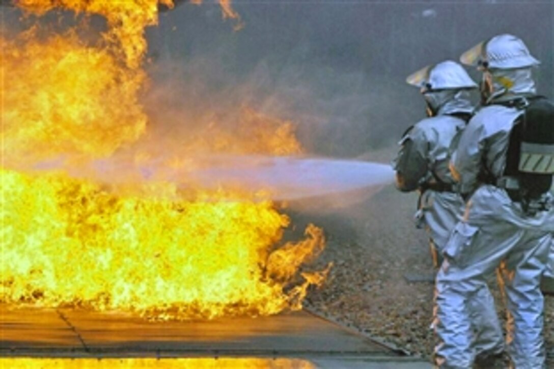 U.S. Air Force airmen extinguish a flare up below an aircraft's wing during a training exercise at the Woensdrecht Firefighting Training Facility in the Netherlands, April 3, 2009. The airmen are assigned to the 309th Airlift Squadron from Chievres Air Base, Belgium.