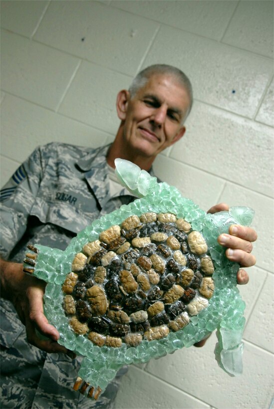 Chief Master Sgt. Dan Cogar, 44th Aerial Port Squadron, presents a turtle he created from glass he collected on the beach. (Air Force photo/Staff. Sgt. Jennie Chamberlin) 