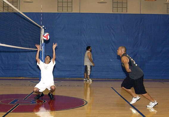ANDERSEN AIR FORCE BASE, Guam -- Tech. Sgt. Paiea Suganuma, 36th Logistics Readiness Squadron noncommissioned officer in charge of resource control center, sets the volleyball so Senior Airman Lawrence Chargualaf, 734th Air Mobility Squadron aircraft maintenance electrician and environmental journeyman, can spike it during the first day of volleyball tryouts held April 7 at the Coral Reef Fitness Center gym. Approximately 45 Team Andersen members participated in the four-day tryouts. (U.S. Air Force photo by Airman Carissa Wolff)                             