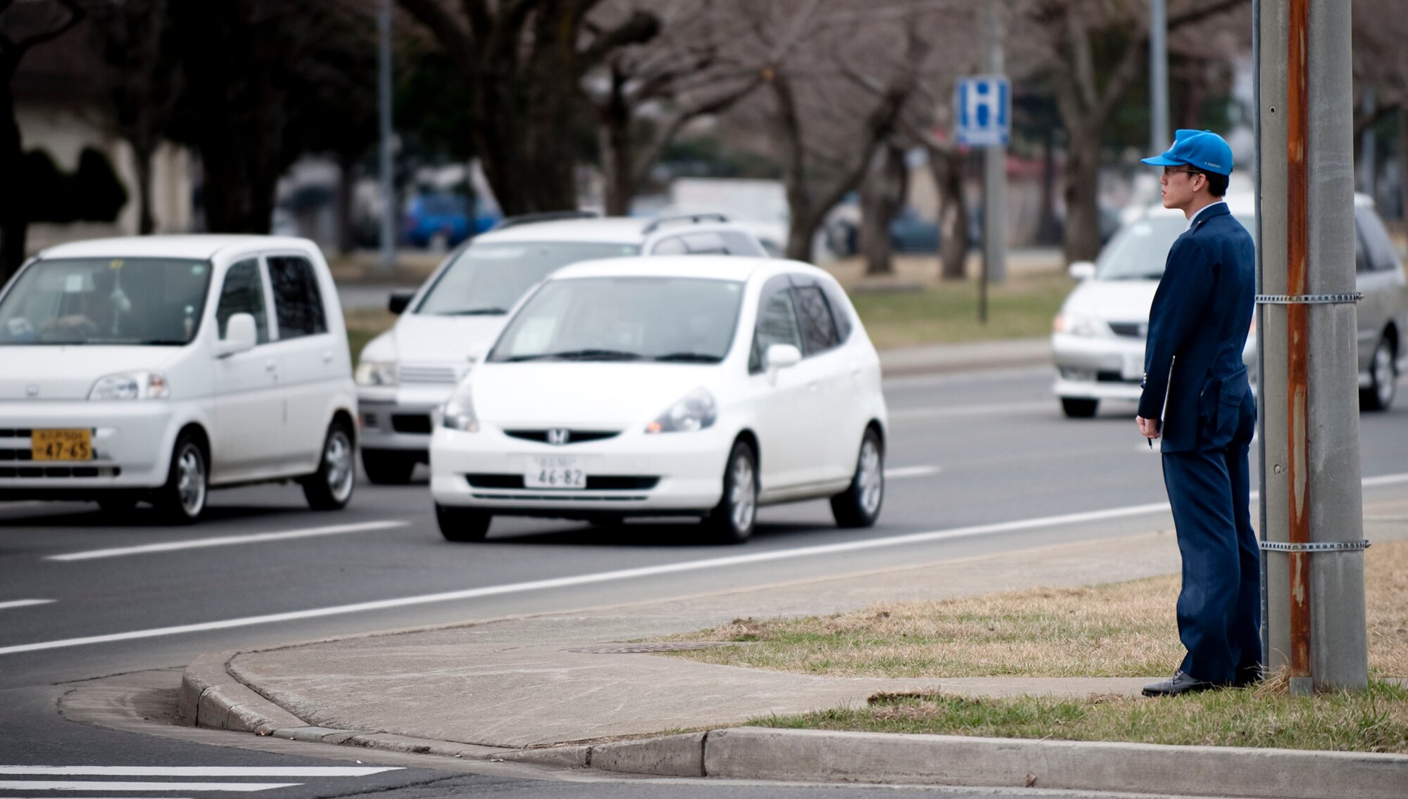 MISAWA AIR BASE, Japan -- A member of the Japan Air Self Defense Force monitors morning traffic on base April 10, 2009. To emphasize driving safety, the JASDF and 35th Fighter Wing safety office is conducting a bilateral traffic safety campaign. Morning and afternoon volunteers stand in high-visibility locations to check for seatbelt use and serve as physical reminders to drive safely. (U.S. Air Force photo by Staff Sgt. Samuel Morse)