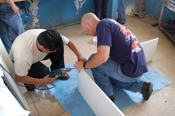 Senior Master Sgt. Greg Moore, 478th Expeditionary Operations Squadron first sergeant, helps a contractor assemble cabinets for the Urbirios community kitchen in Manta, Ecuador Feb. 16. Through the $7,000-worth of donated equipment from U.S. Southern Command’s Humanitarian Assistance Program (HAP), the kitchen may now open its doors to serve more members of the community better quality and portions of food. (U.S. Air Force photo by 1st Lt. Beth Woodward)