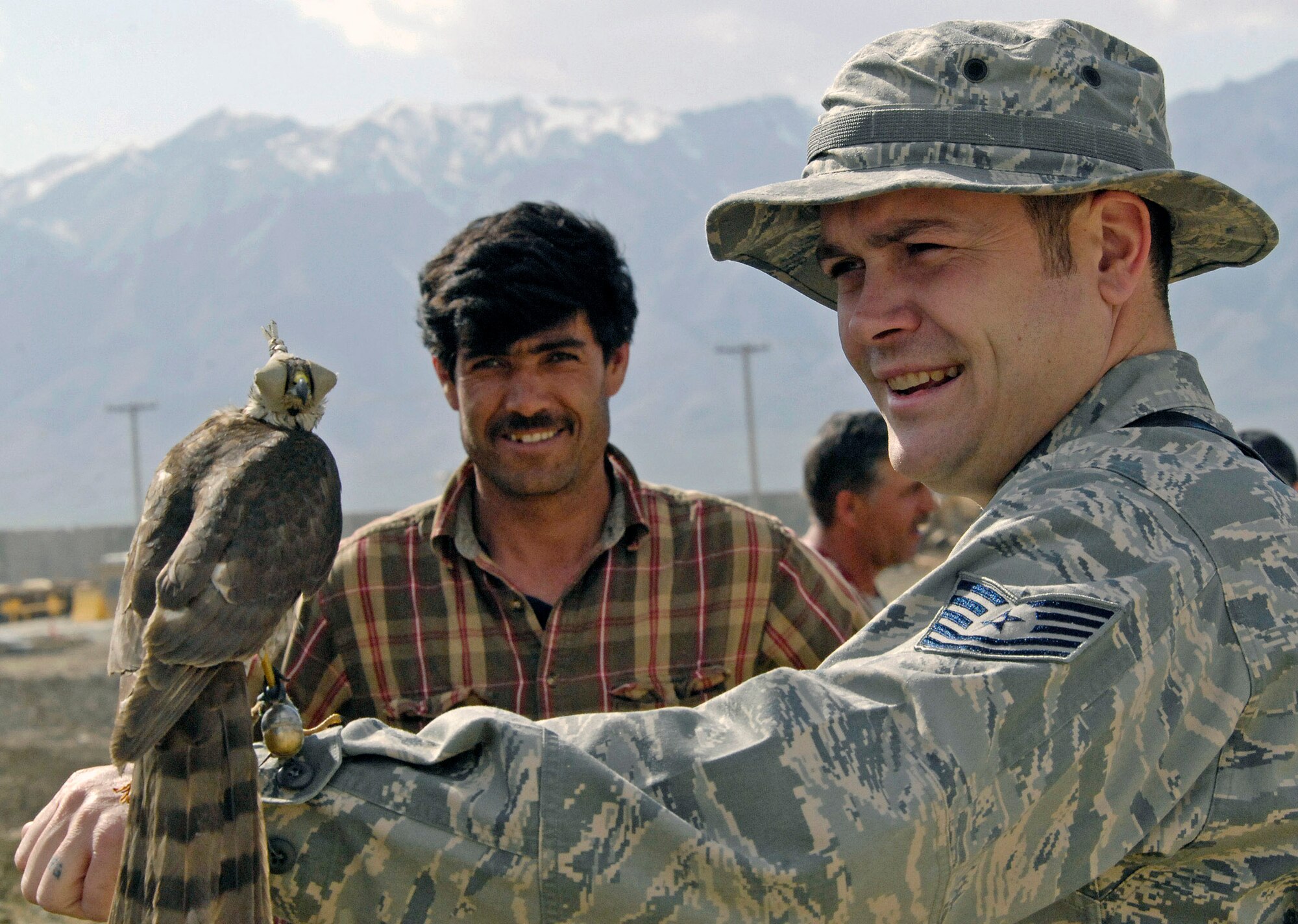 Tech. Sgt. Shane Sweeney holds out a falcon trained by a local Afghan falconer to catch much larger black kite birds that have infested areas near the flightline March 29 at Bagram Airfield, Afghanistan. The falcon's feet are rigged with snare traps so that when the larger kite bird attacks it gets tangled with the falcon and falls to the ground. Sergeant Sweeney is a 455th Air Expeditionary Wing weapons safety member. (U.S. Air Force photo/Staff Sgt. Jason Lake) 
